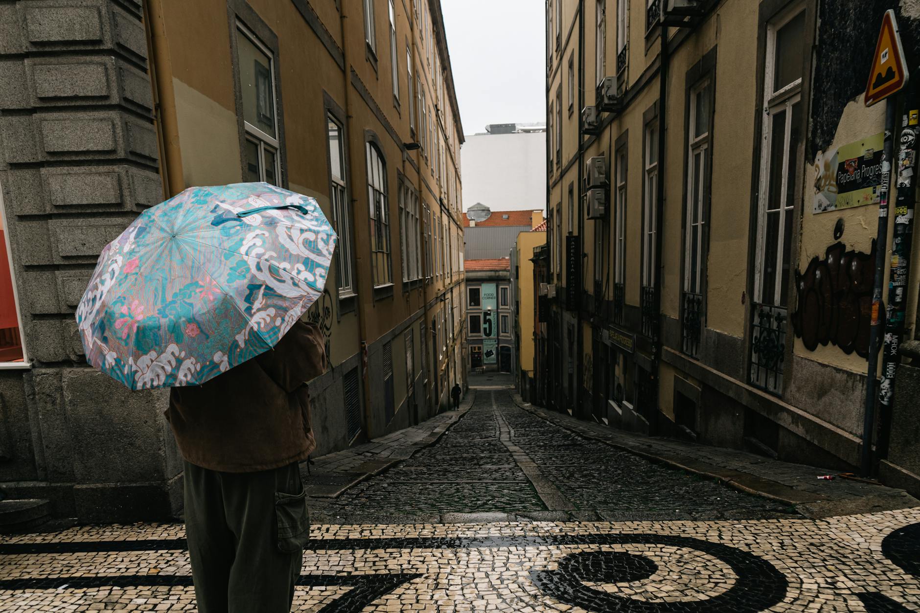 Person with a colorful umbrella on a rainy Porto street