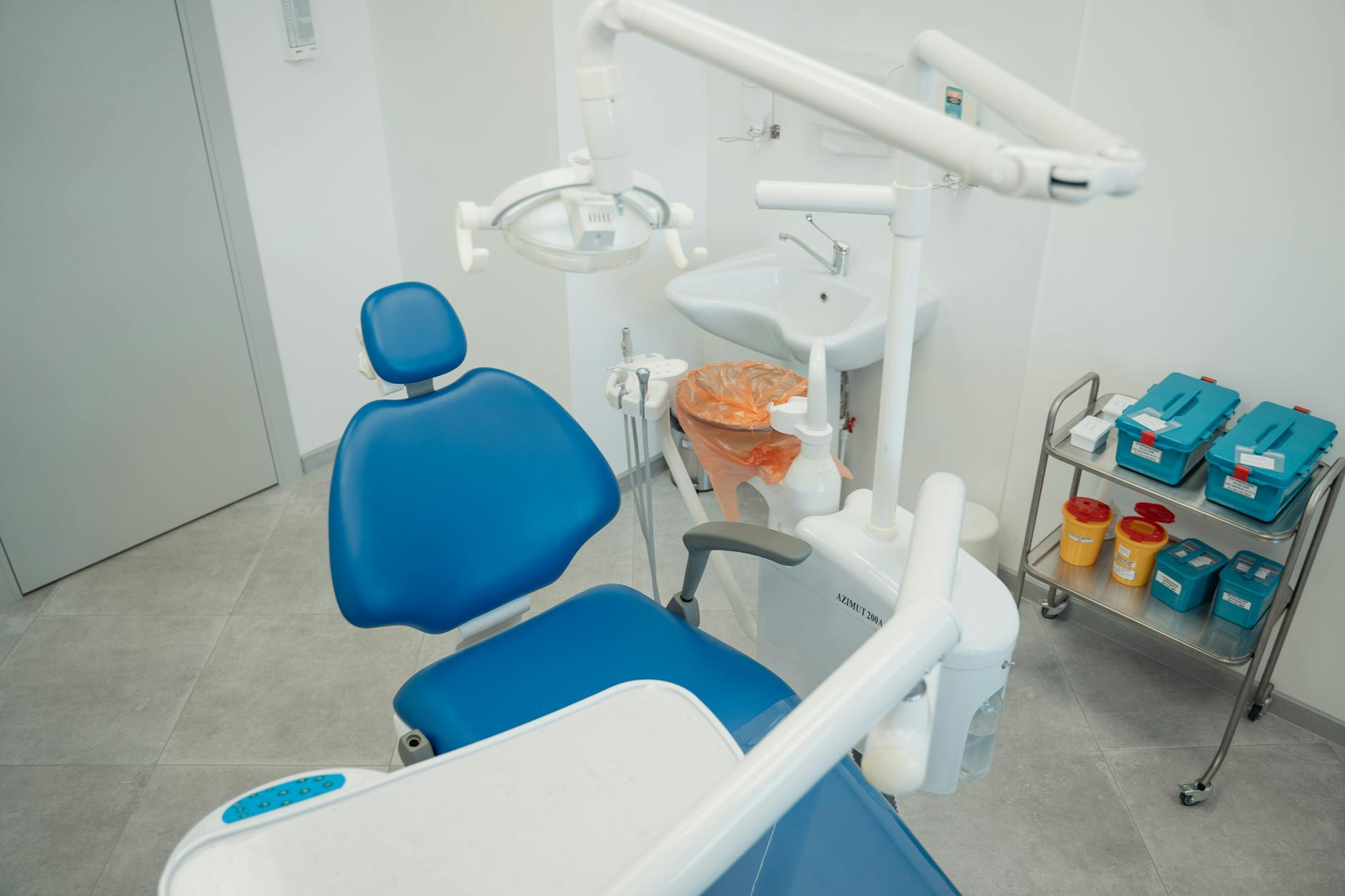 Clean modern clinic room with blue medical chair and equipment
