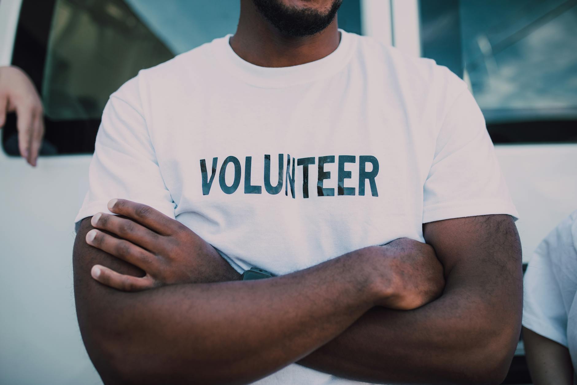 Person wearing a volunteer shirt with arms crossed