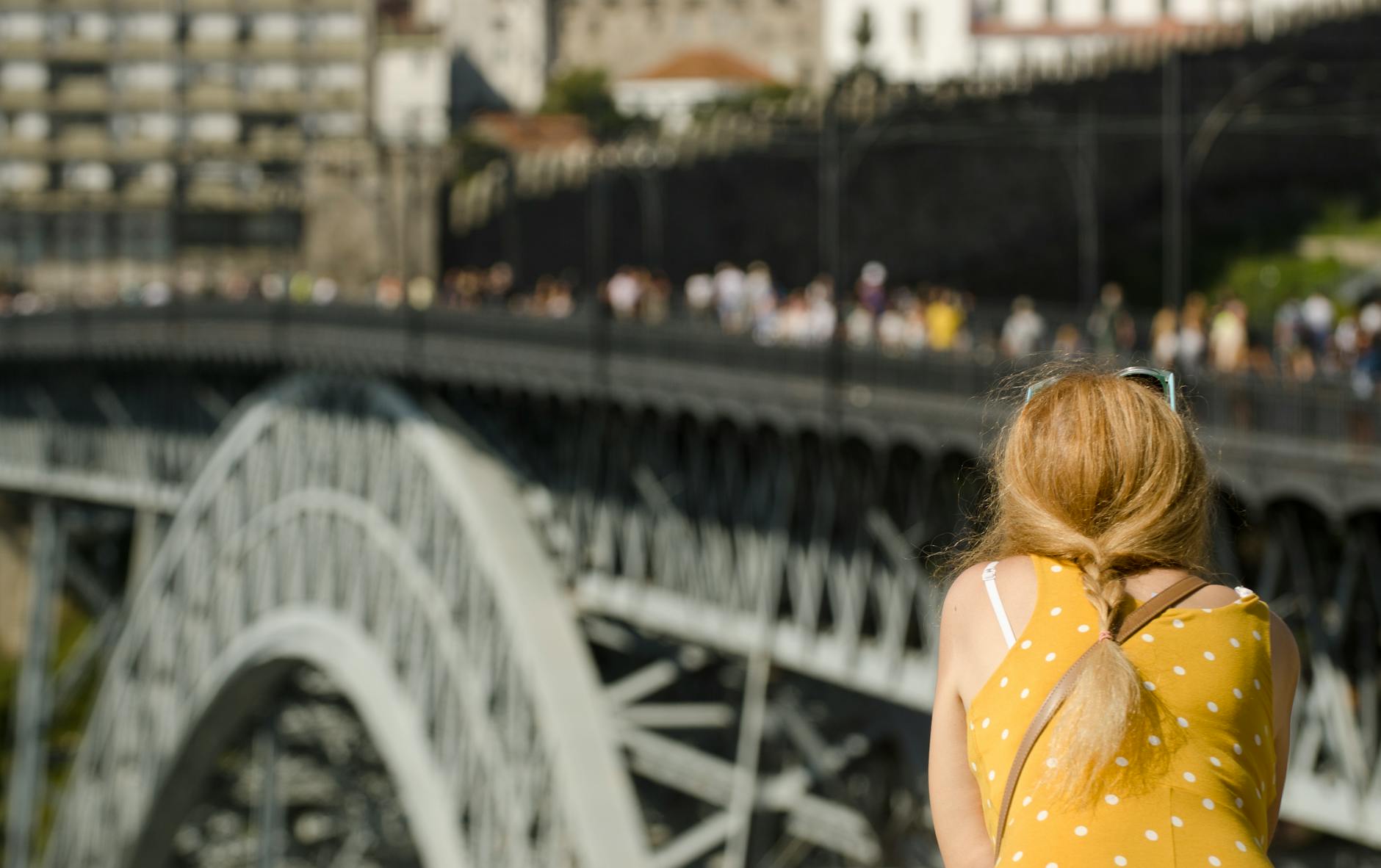 Woman in yellow dress looking at Porto cityscape and iron bridge