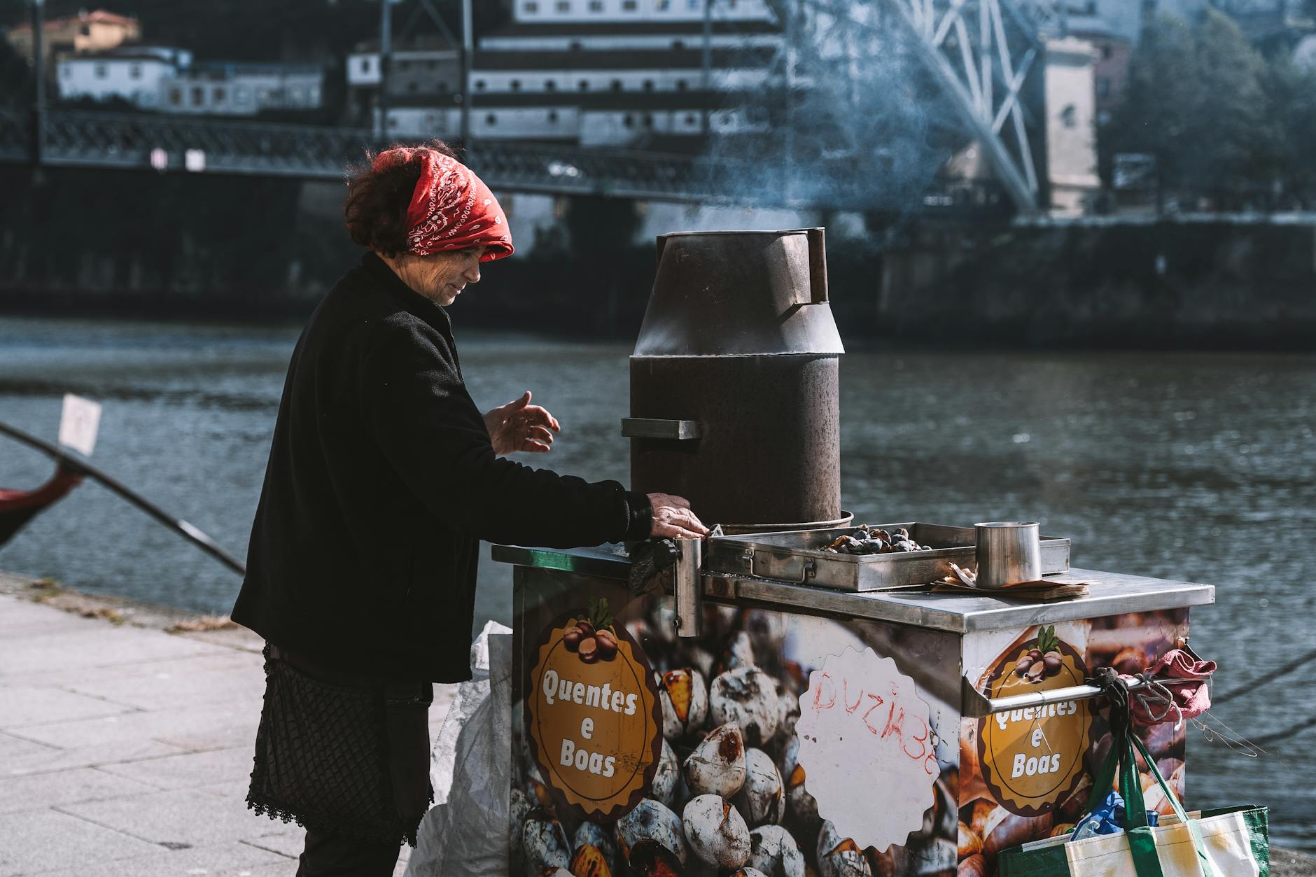 Woman preparing roasted chestnuts by the Douro River in Porto