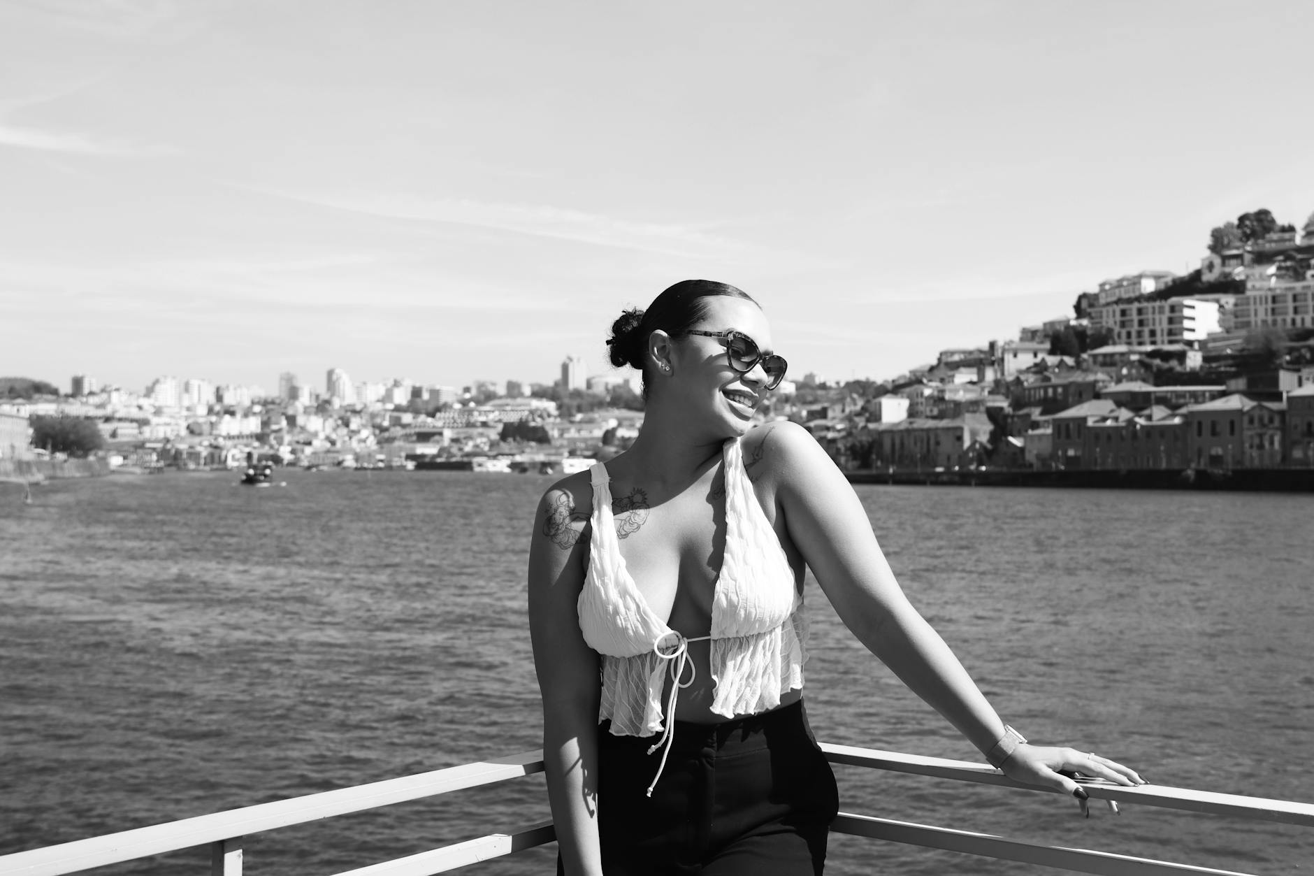 Woman smiling by Porto's waterfront in sunglasses