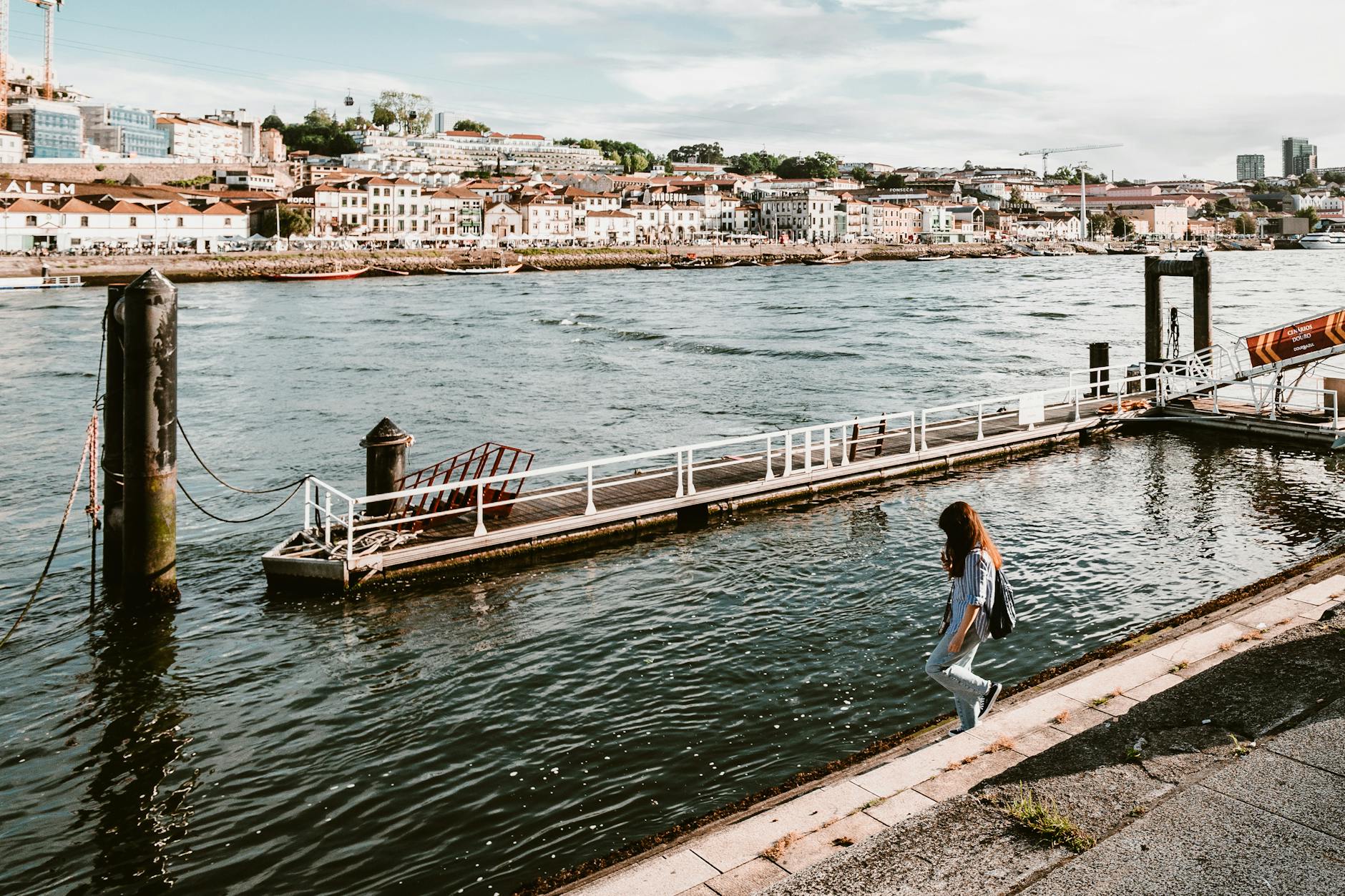 Woman walking by the sunny Porto riverfront