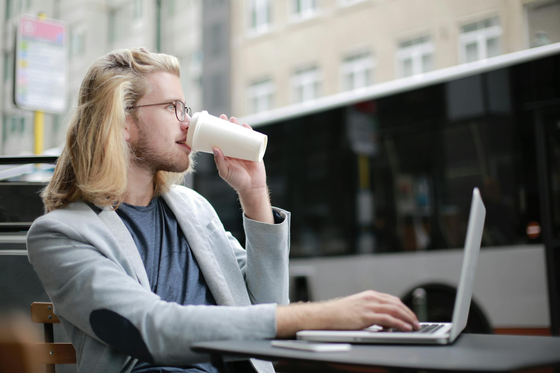 Business traveler working remotely on a laptop with coffee outdoors