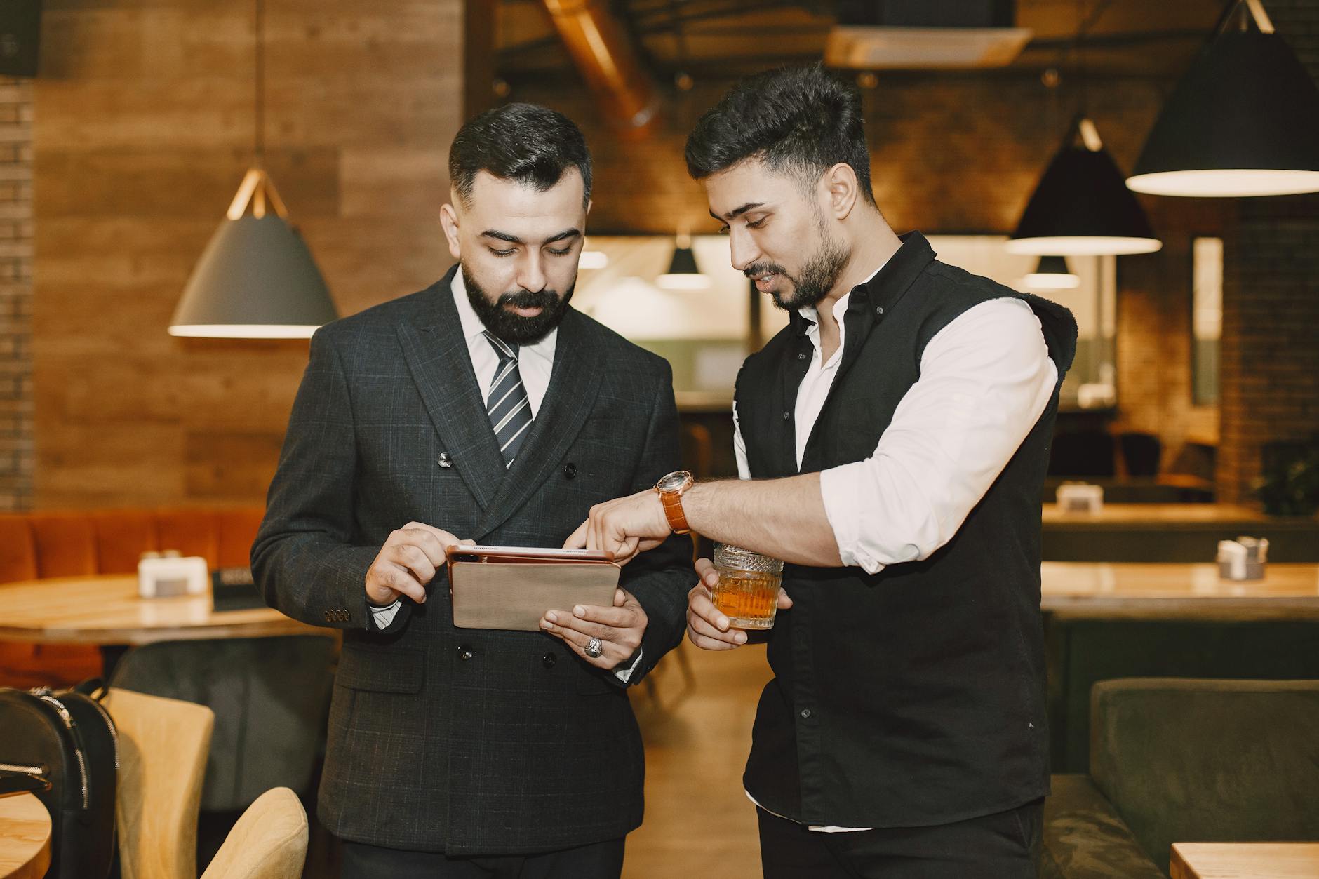Two business travelers discussing work on a tablet in a cafe