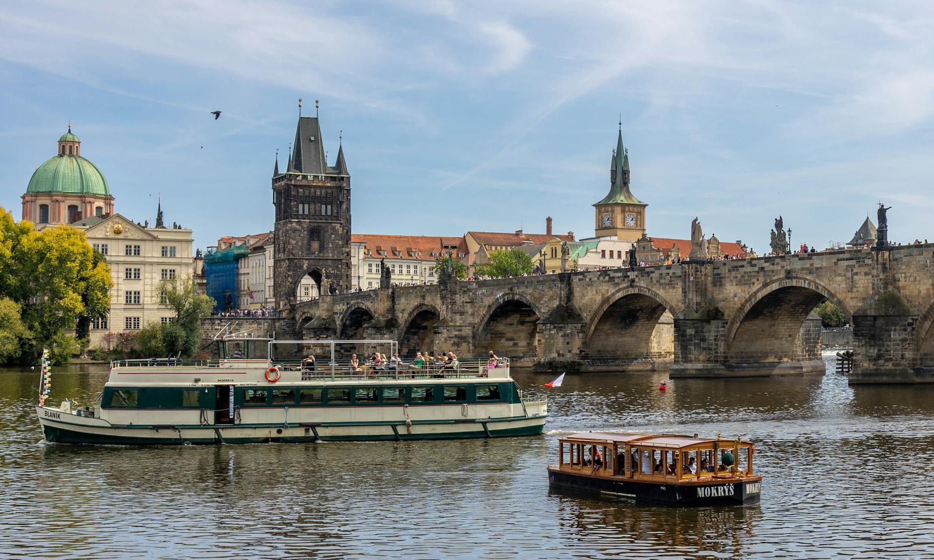 Cruise boat on the Vltava River with Charles Bridge in Prague