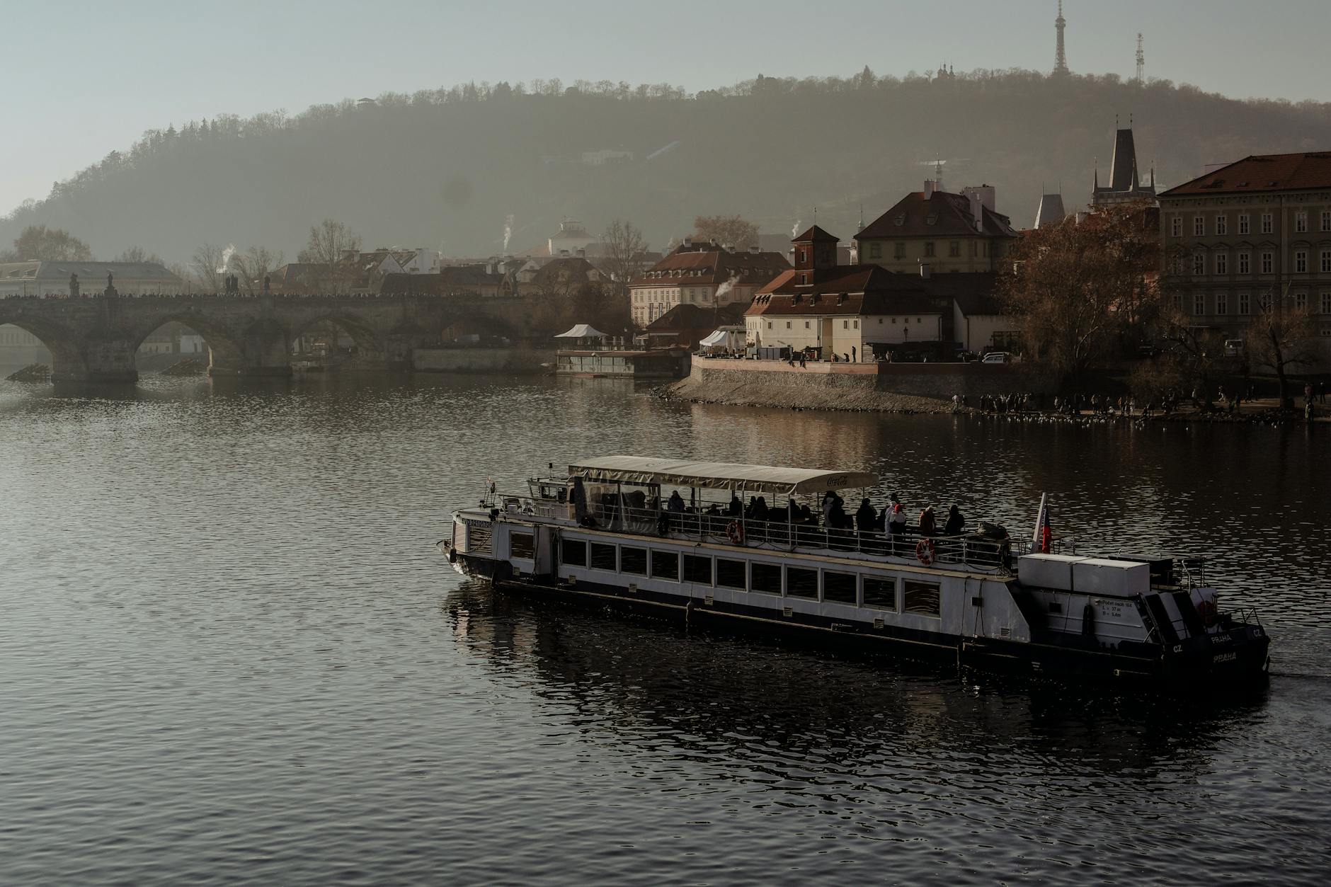 Boat on the Vltava River with Charles Bridge and Prague skyline