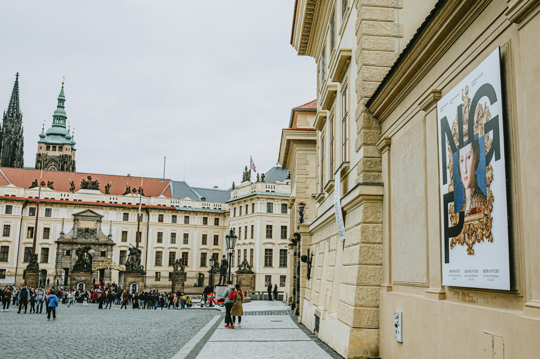 Tourists exploring Prague Castle courtyard with St. Vitus Cathedral