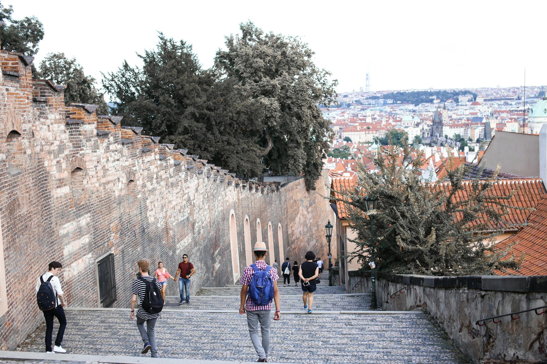 Tourists walking along Prague Castle walls with city views
