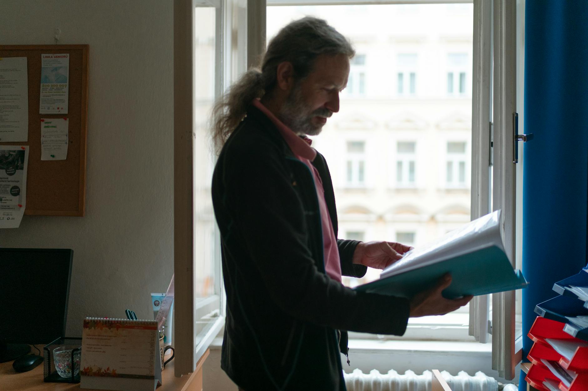Man reviewing documents in a Prague office by a window