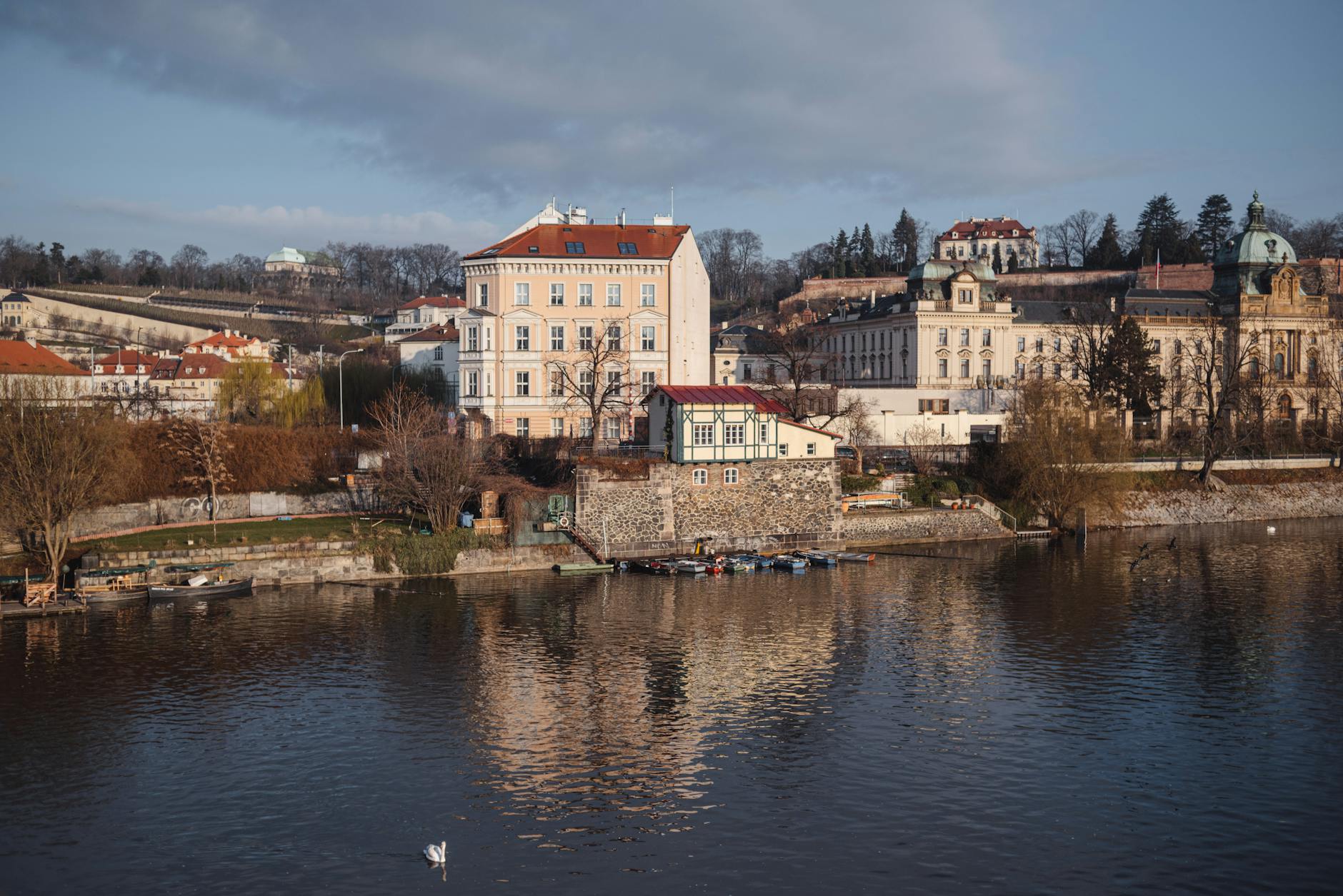 Prague residential buildings along a calm river with trees