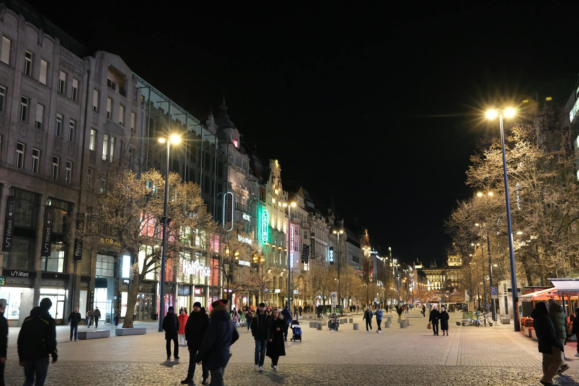 Busy Prague street at night with city lights and historic architecture