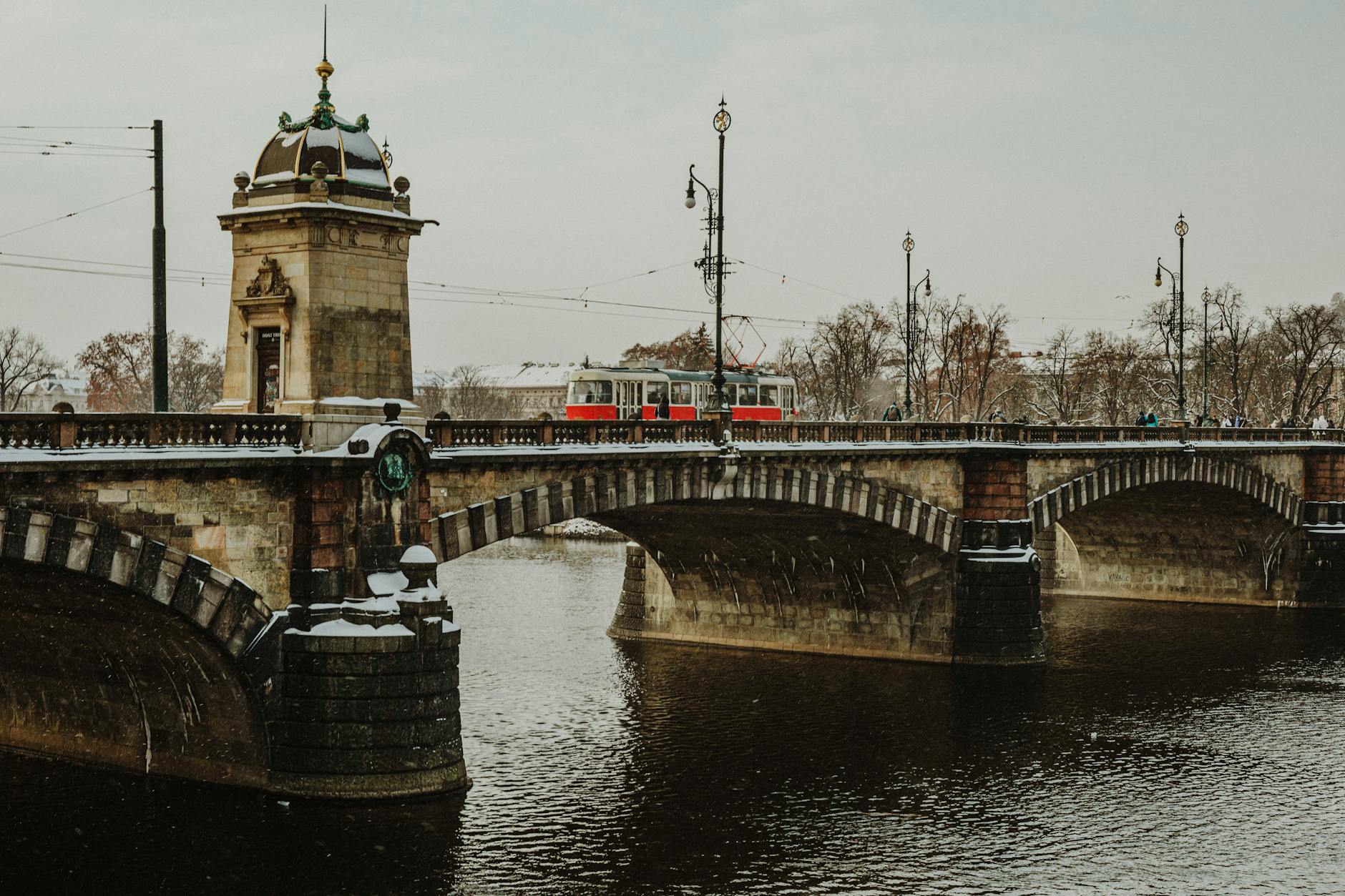 Snow-covered Legion Bridge with tram in Prague