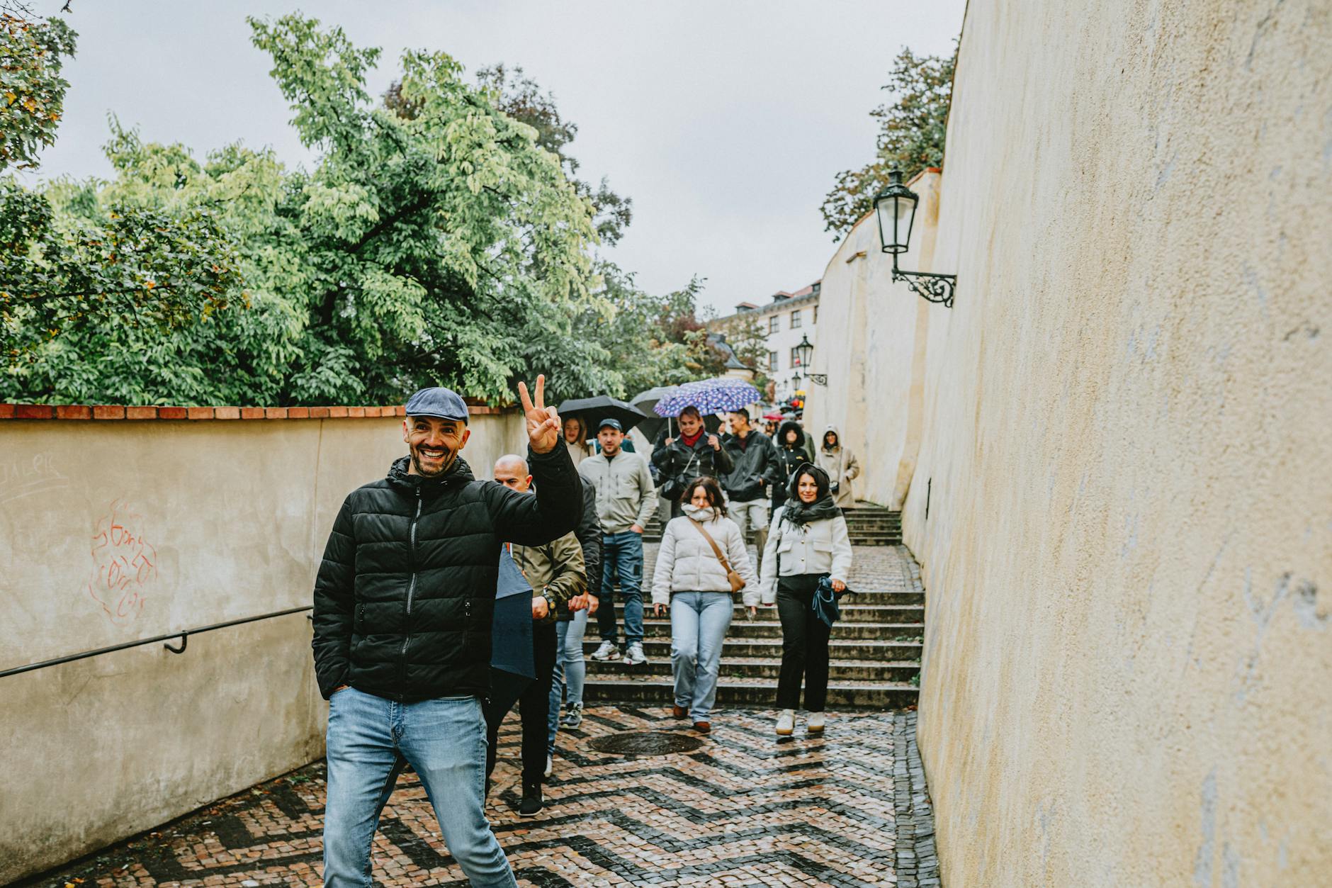 Tourists walking down historic steps in Prague on a rainy day