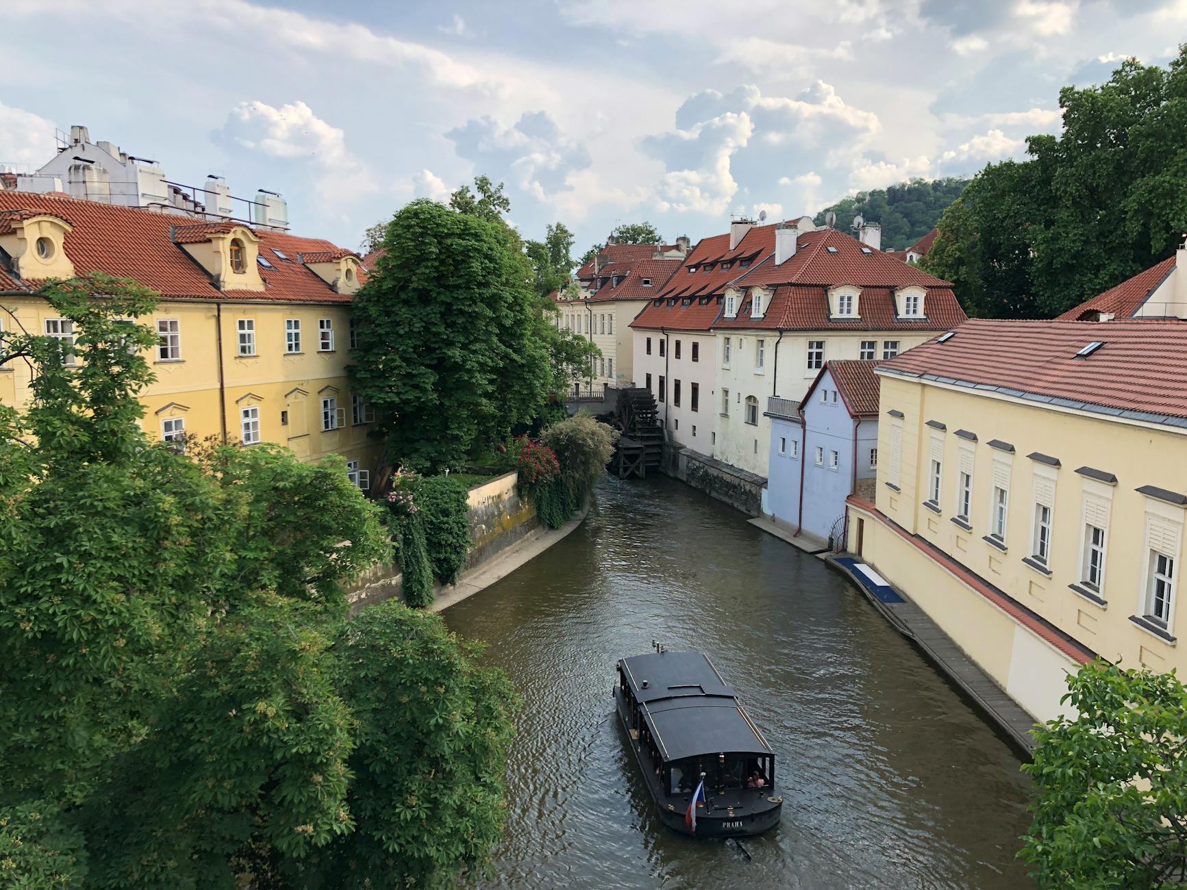 Boat on the Vltava River beside Prague buildings and a canal