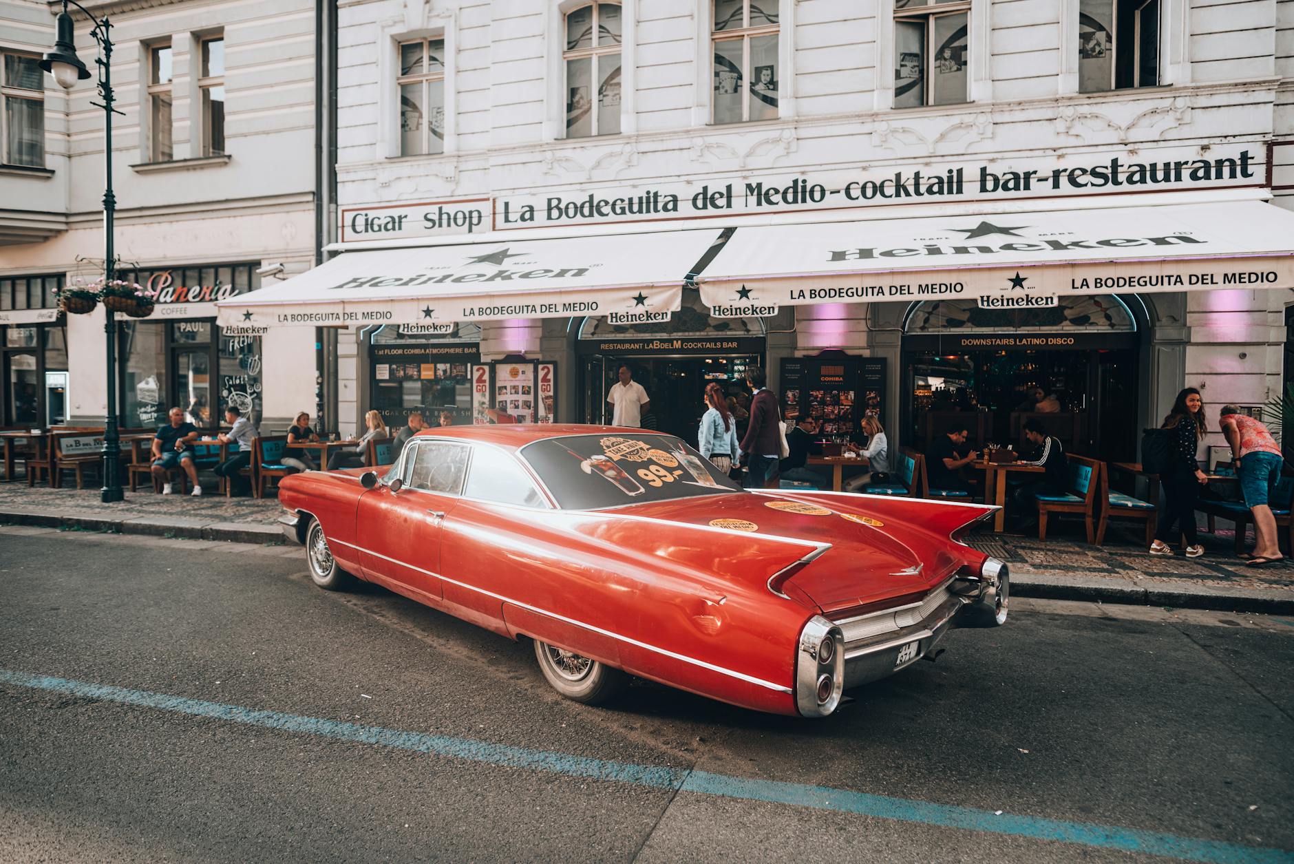 Vintage red car parked outside a cafe on a Prague street