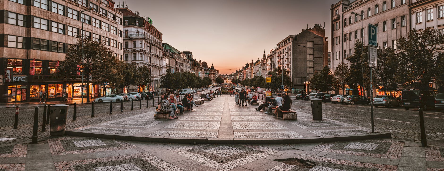 Busy Prague street at sunset with cars and historic buildings