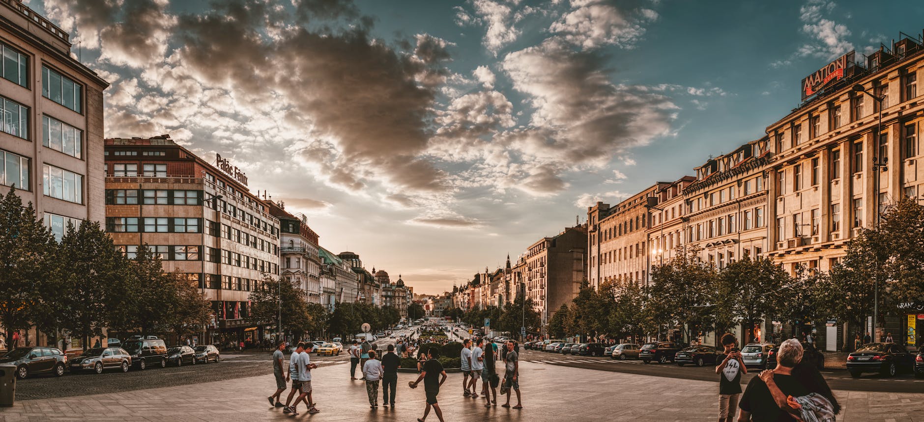 Lively Prague square at sunset with people and historic buildings