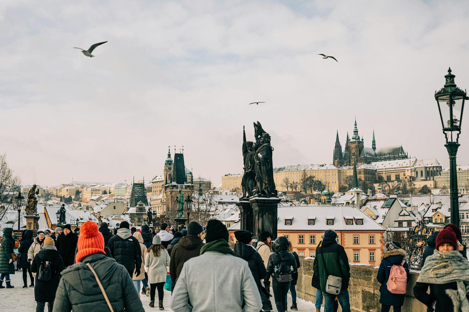 Tourists crossing Charles Bridge with Prague Castle in the background