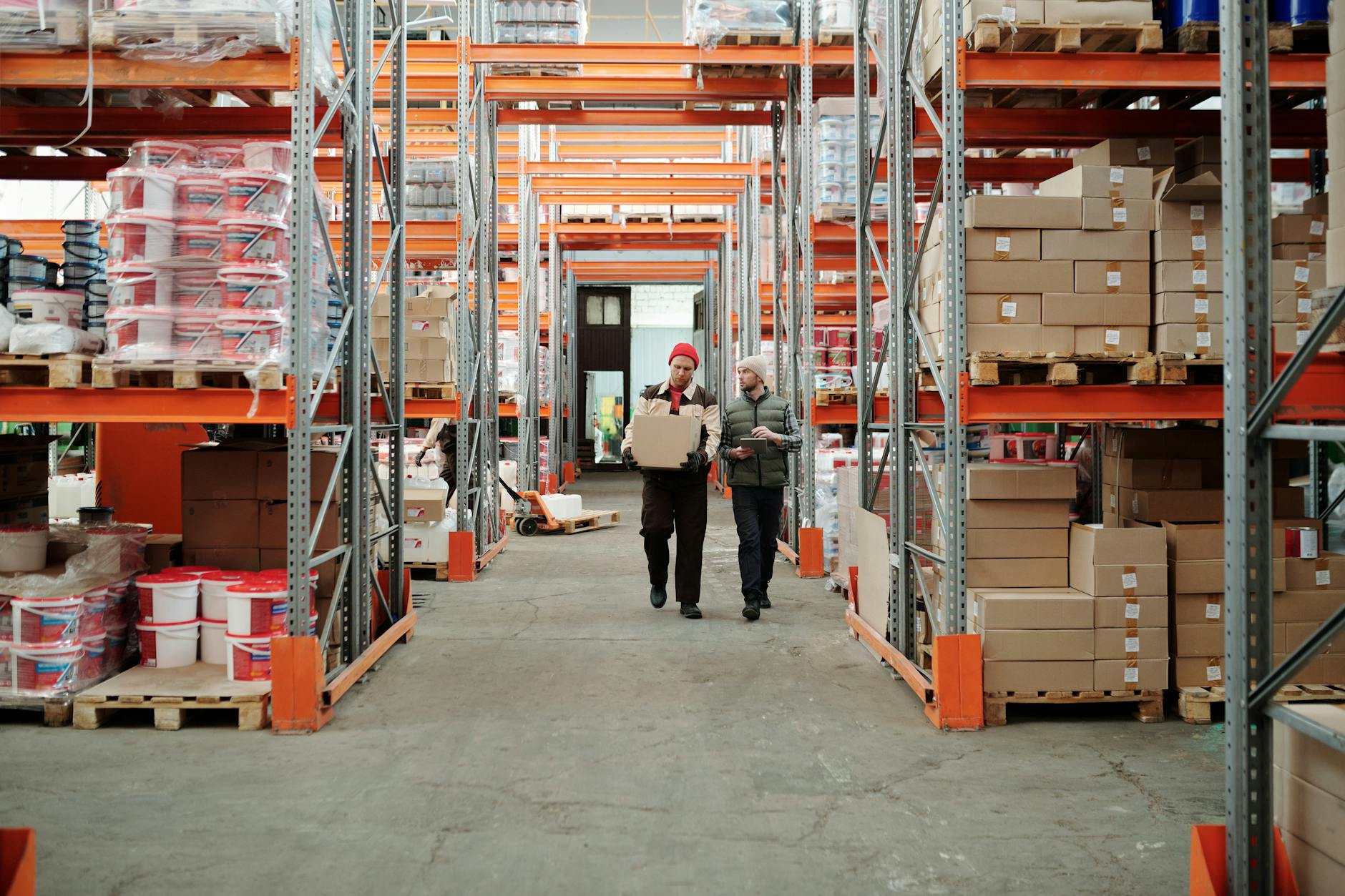 Workers moving packages in a warehouse aisle
