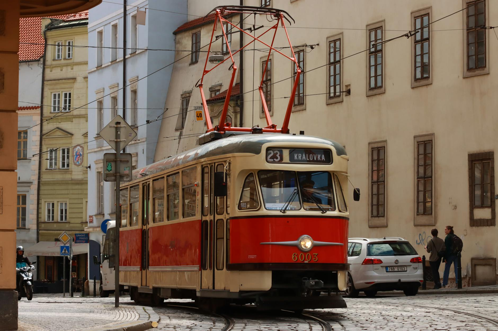 Red tram moving through a historic Prague street