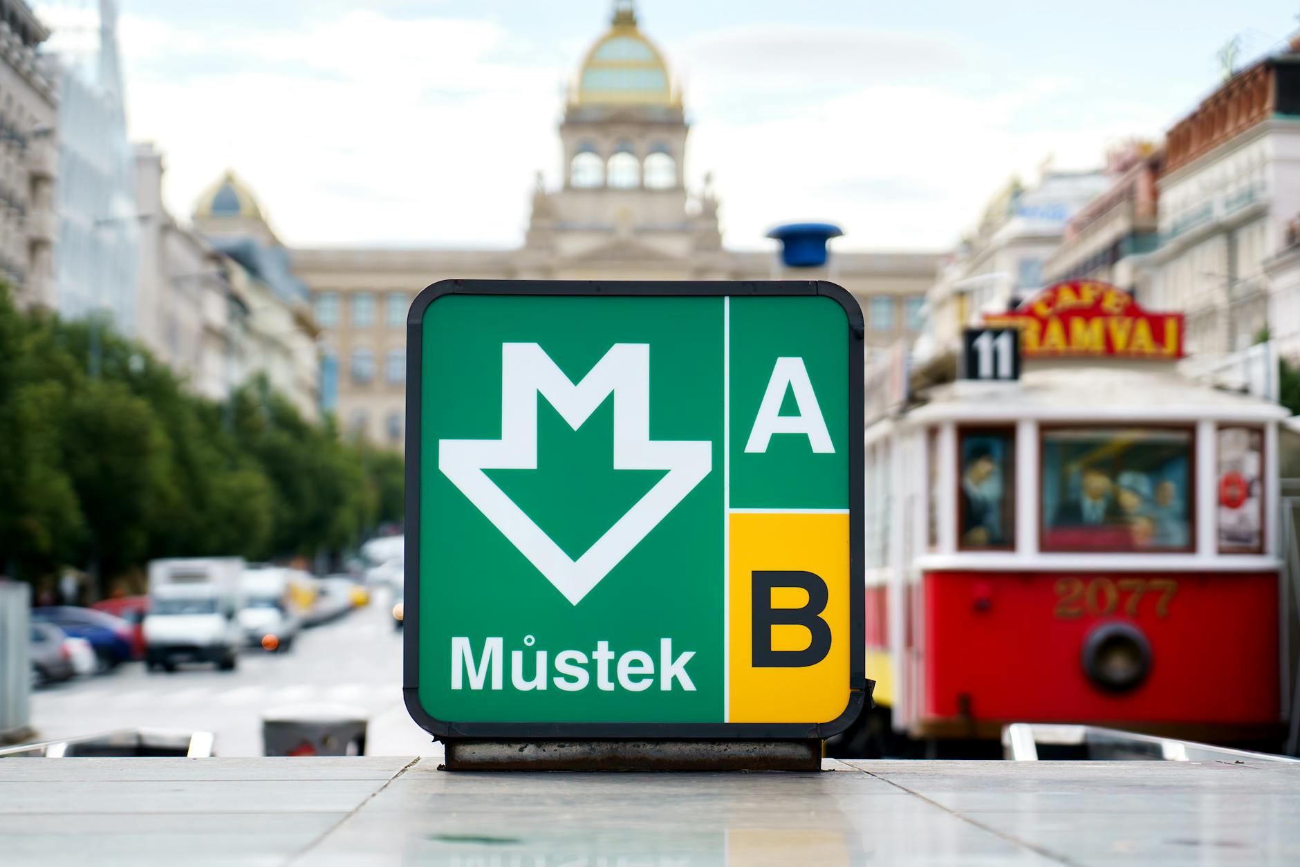 Prague metro sign and tram in a busy city center