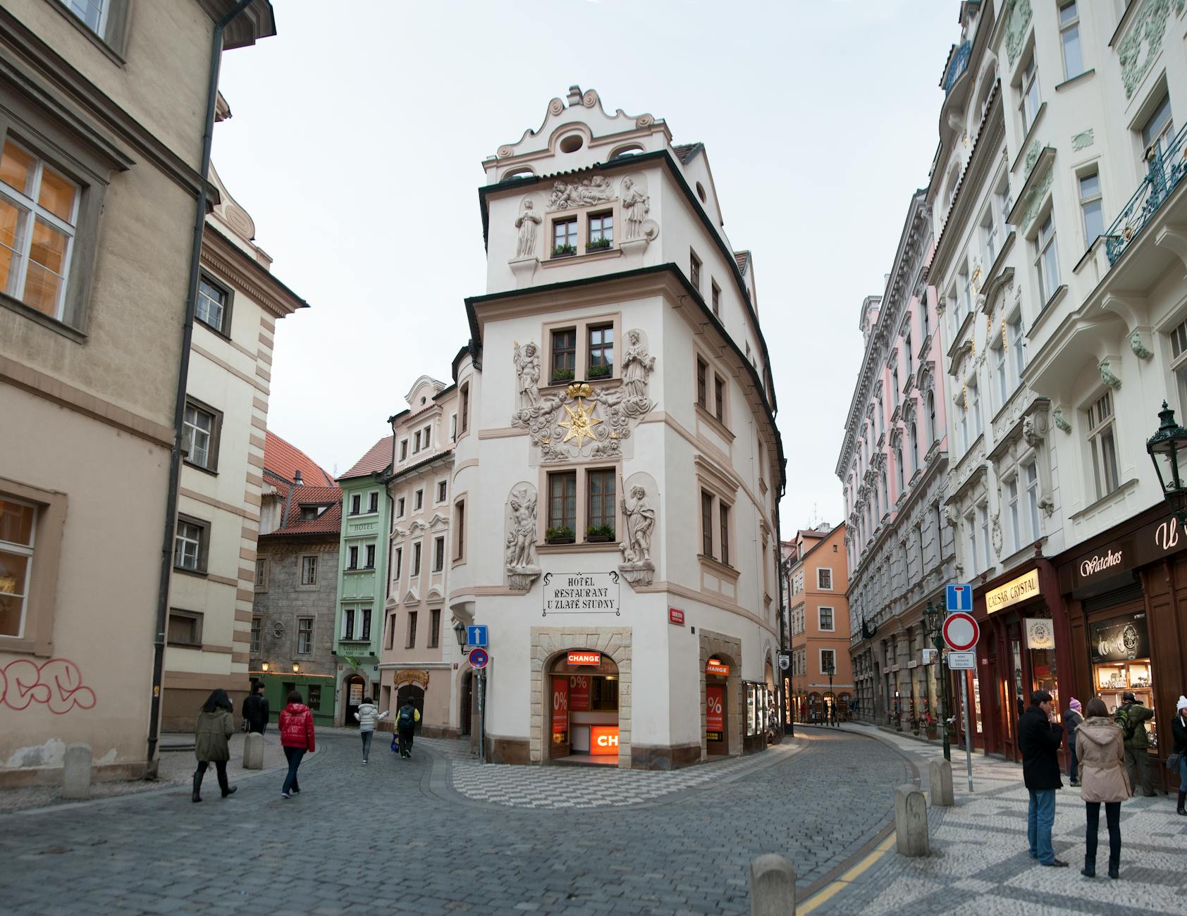 People walking on a historic Prague street near a hotel