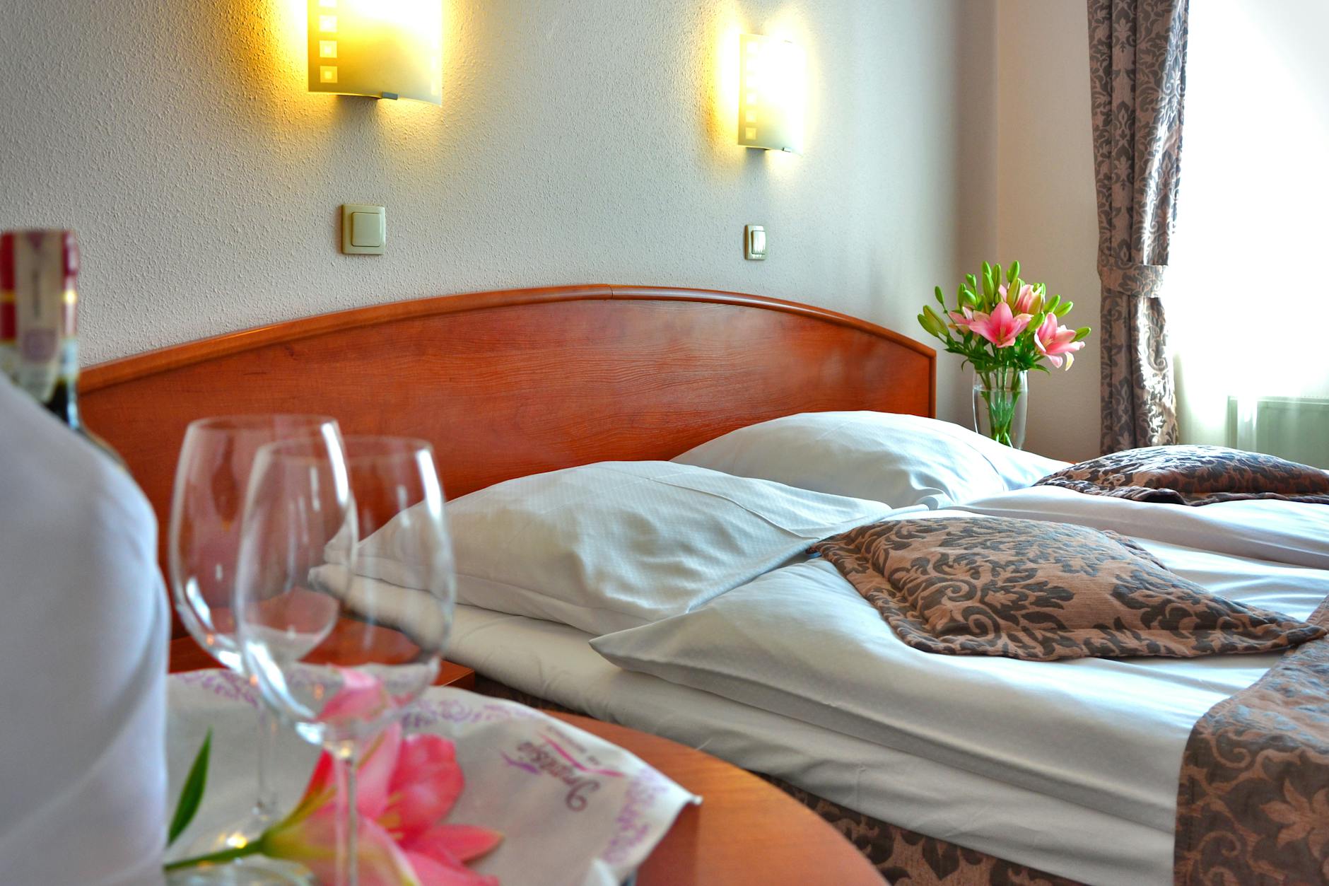 Hotel room with bed, table, and glasses arranged for a quiet stay