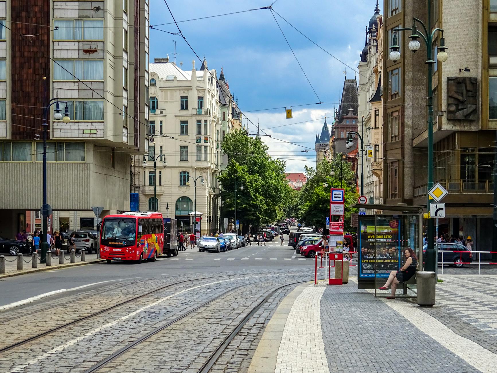 Prague street scene with historic architecture, vehicles, and pedestrians