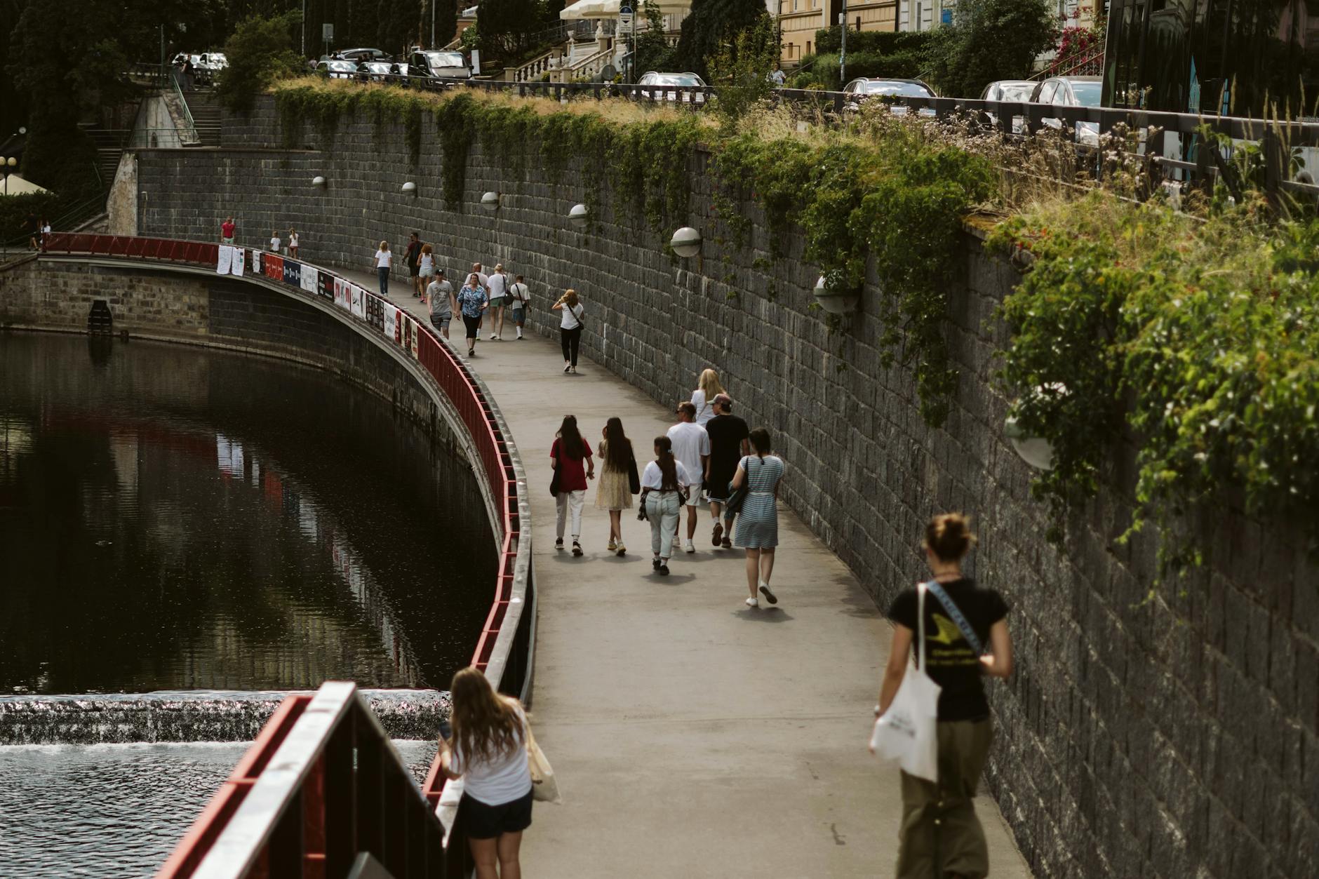Pedestrians walking along an urban riverside pathway