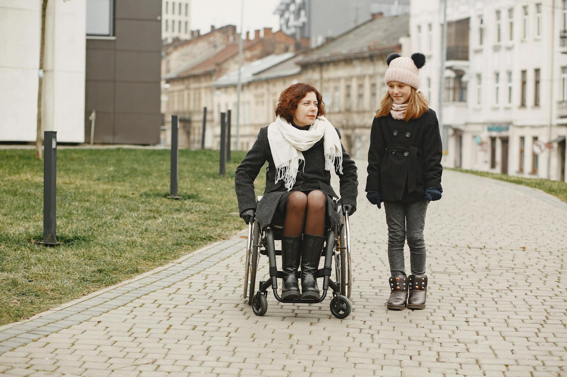 Woman using a wheelchair on a cobbled urban path with a companion