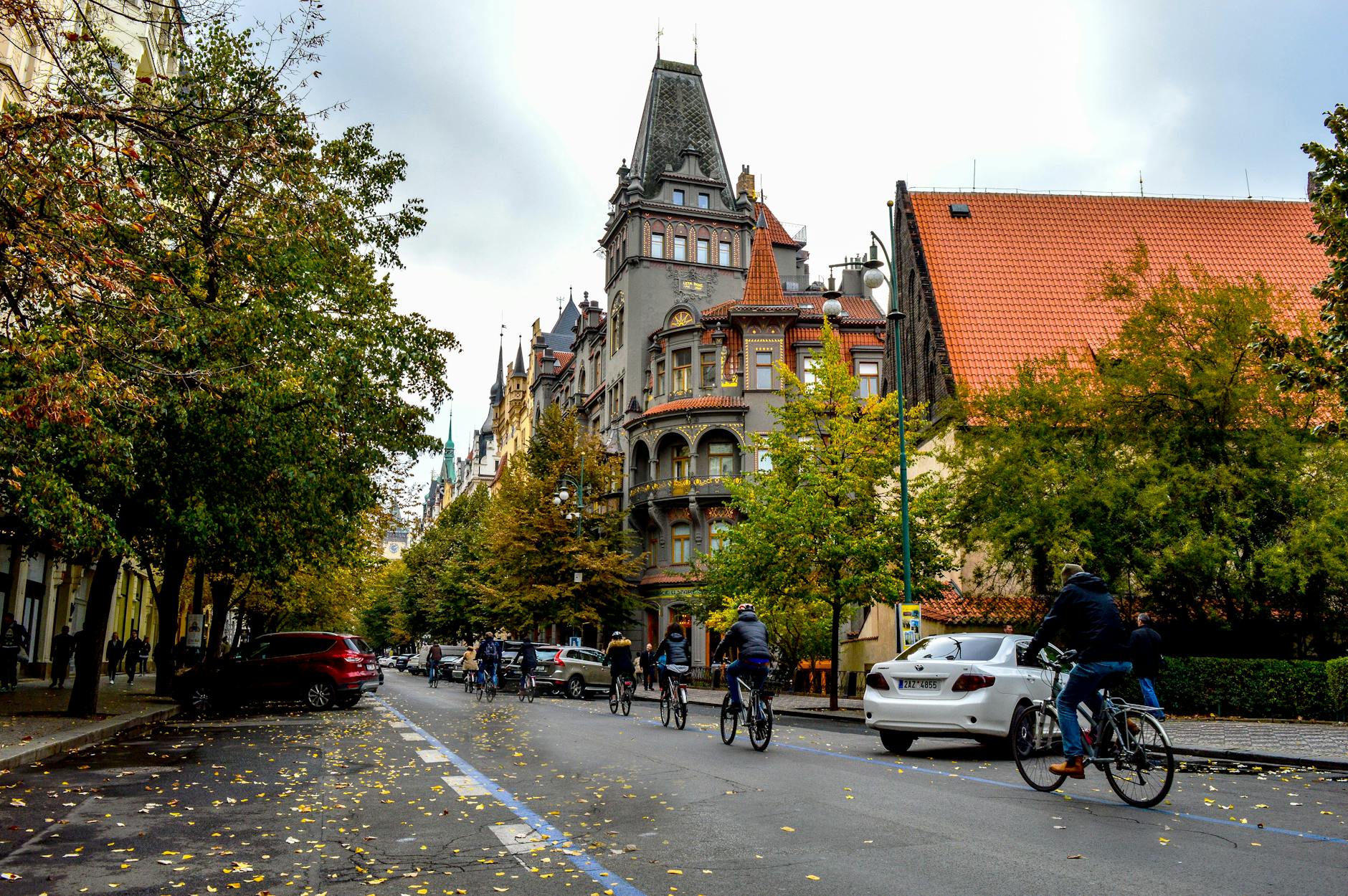 Cyclists riding through a Prague street with historic buildings