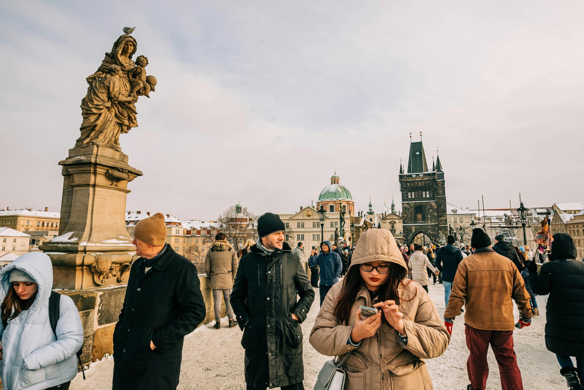 Tourists walking across Charles Bridge in snowy Prague