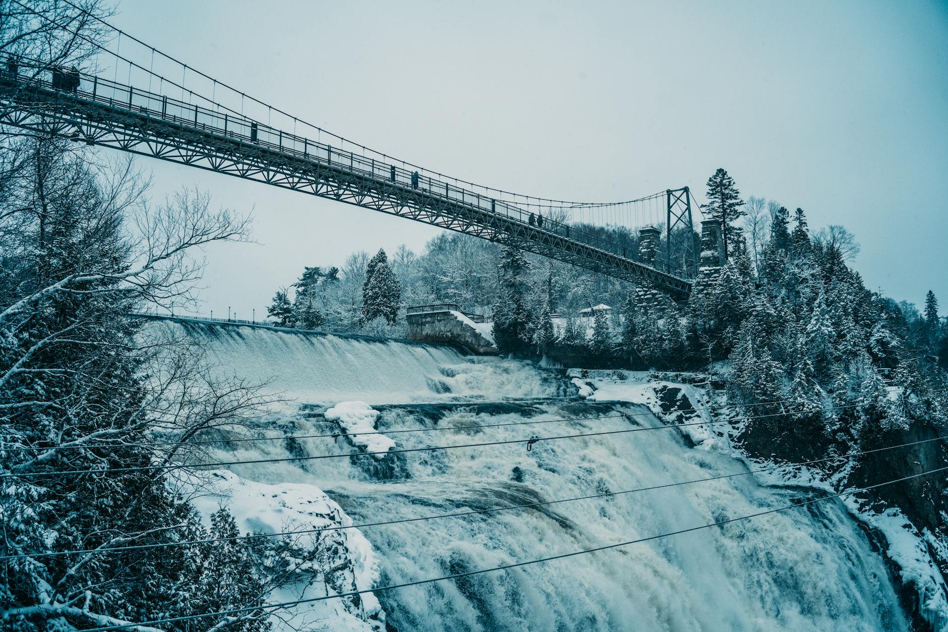 Snowy winter view of Montmorency Falls and suspension bridge in Quebec