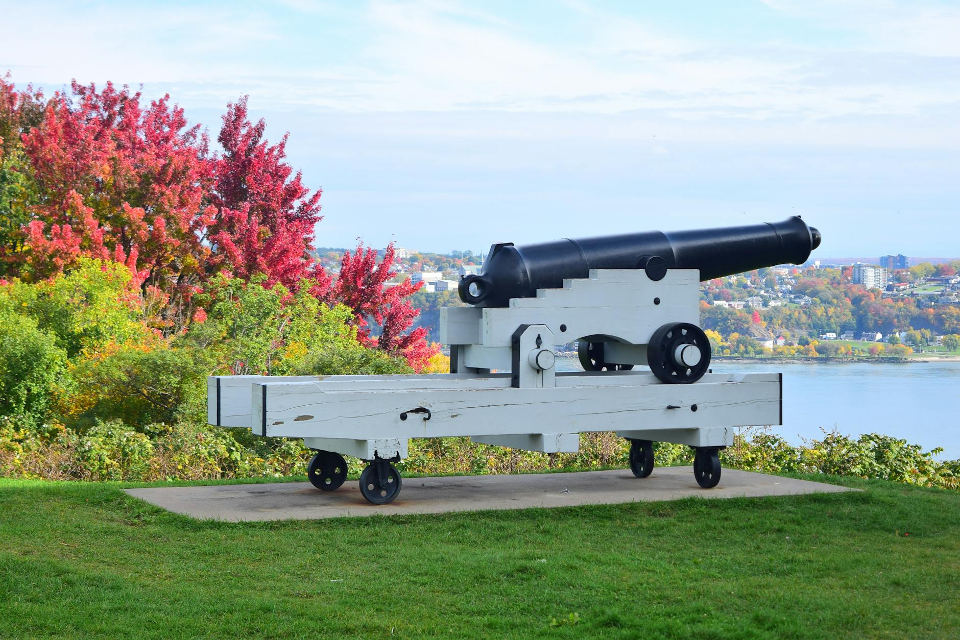 Historic cannon overlooking a river and autumn foliage