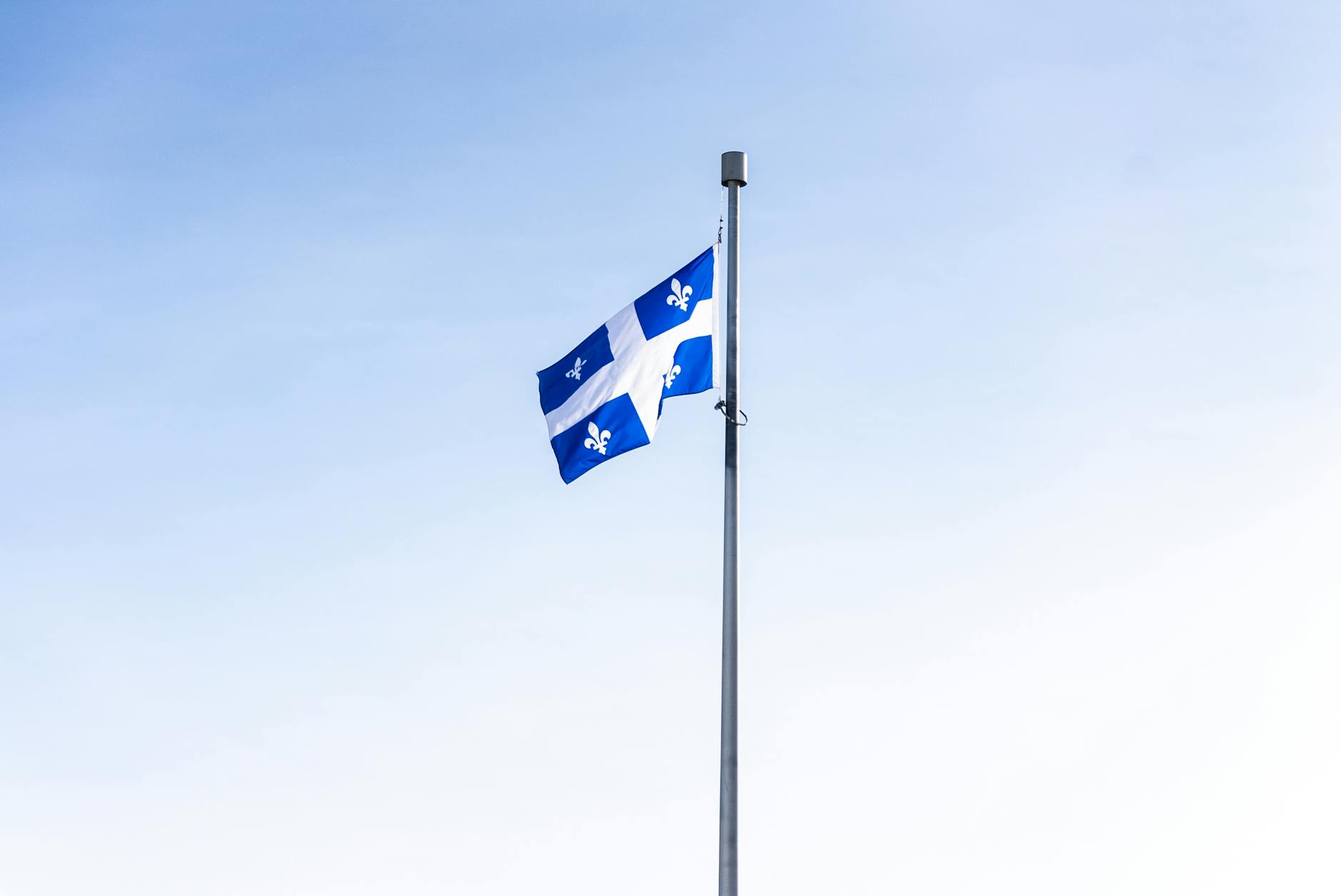 Quebec flag waving against a clear blue sky