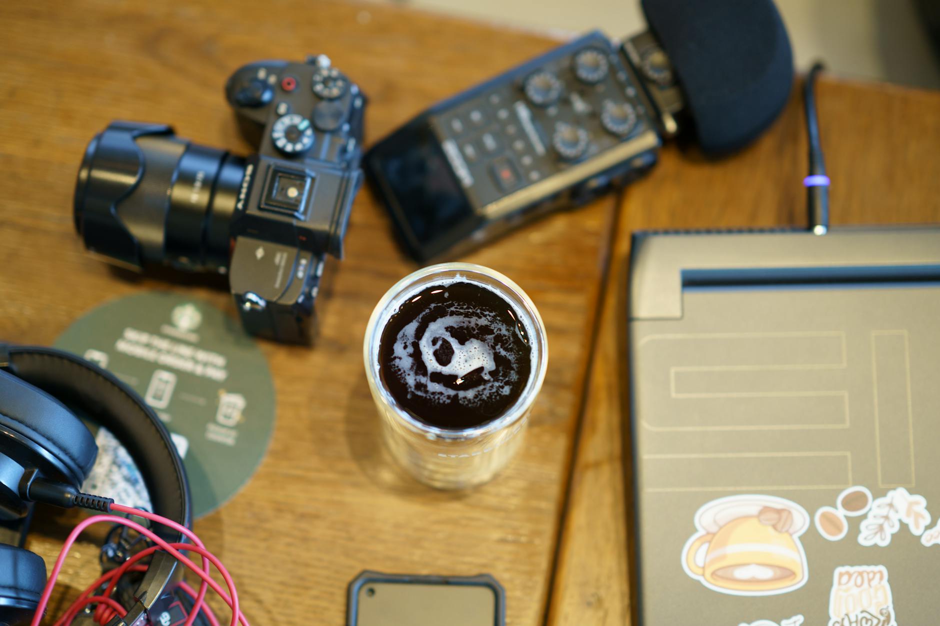 Workspace with camera, headphones, audio gear, and coffee