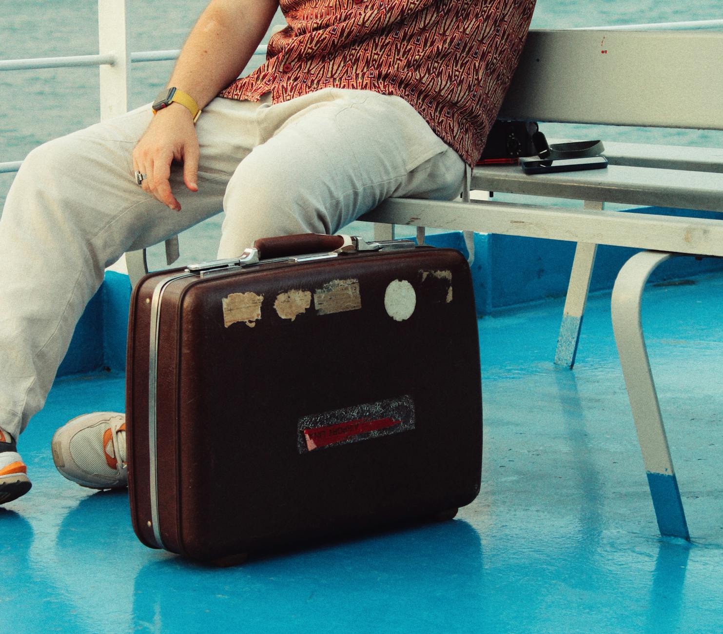 Traveler sitting on a ferry with a vintage suitcase