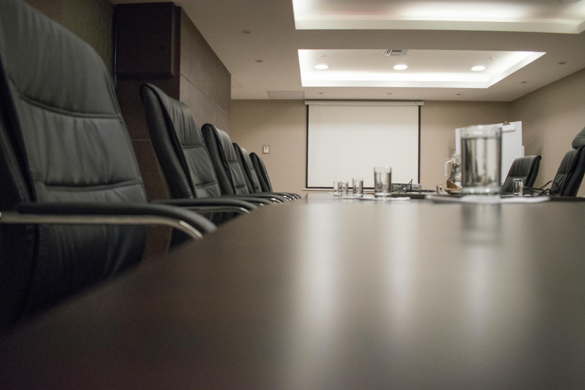 Empty conference room with chairs, projector, and glasses on a table