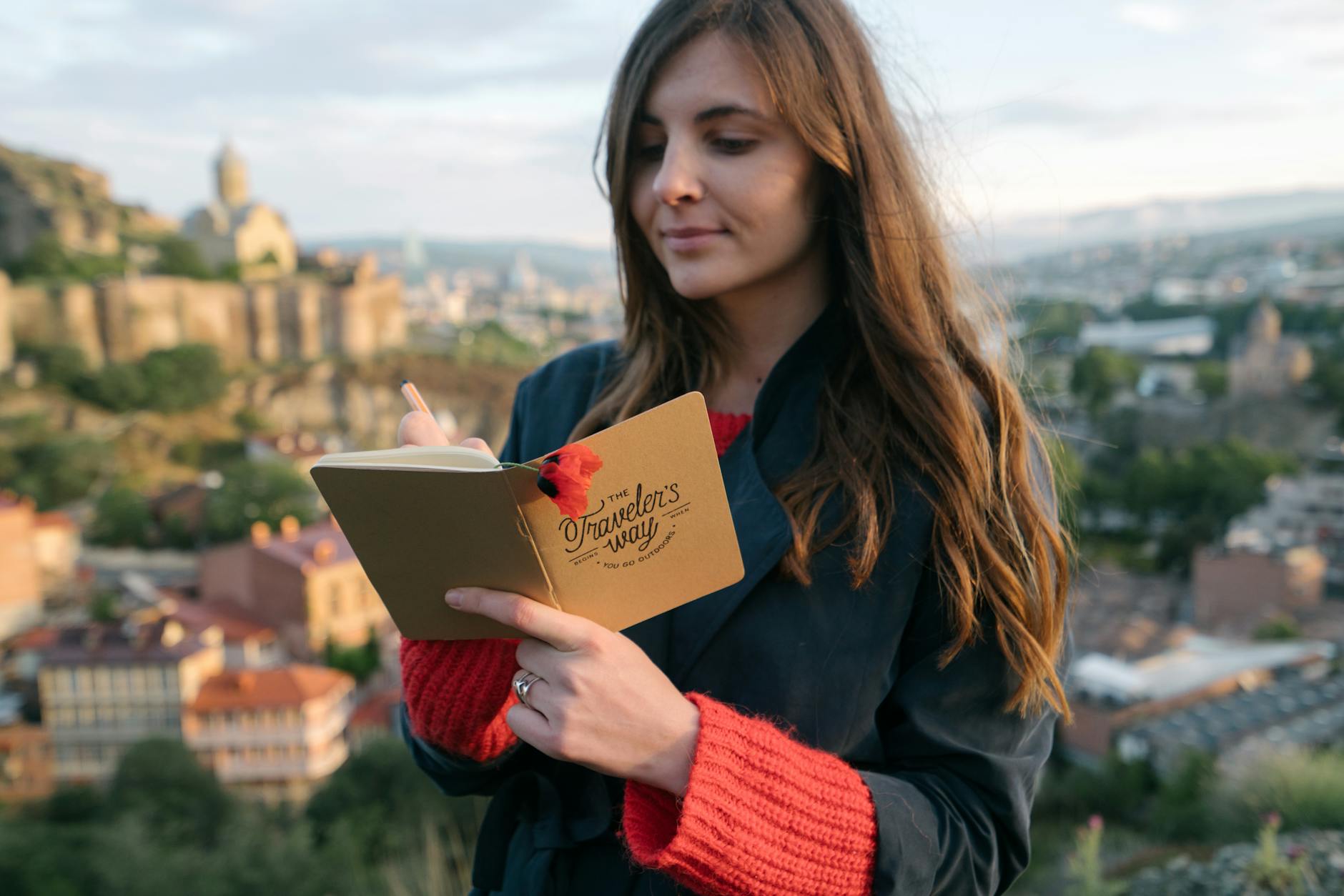 Woman writing in a journal with a historic city backdrop