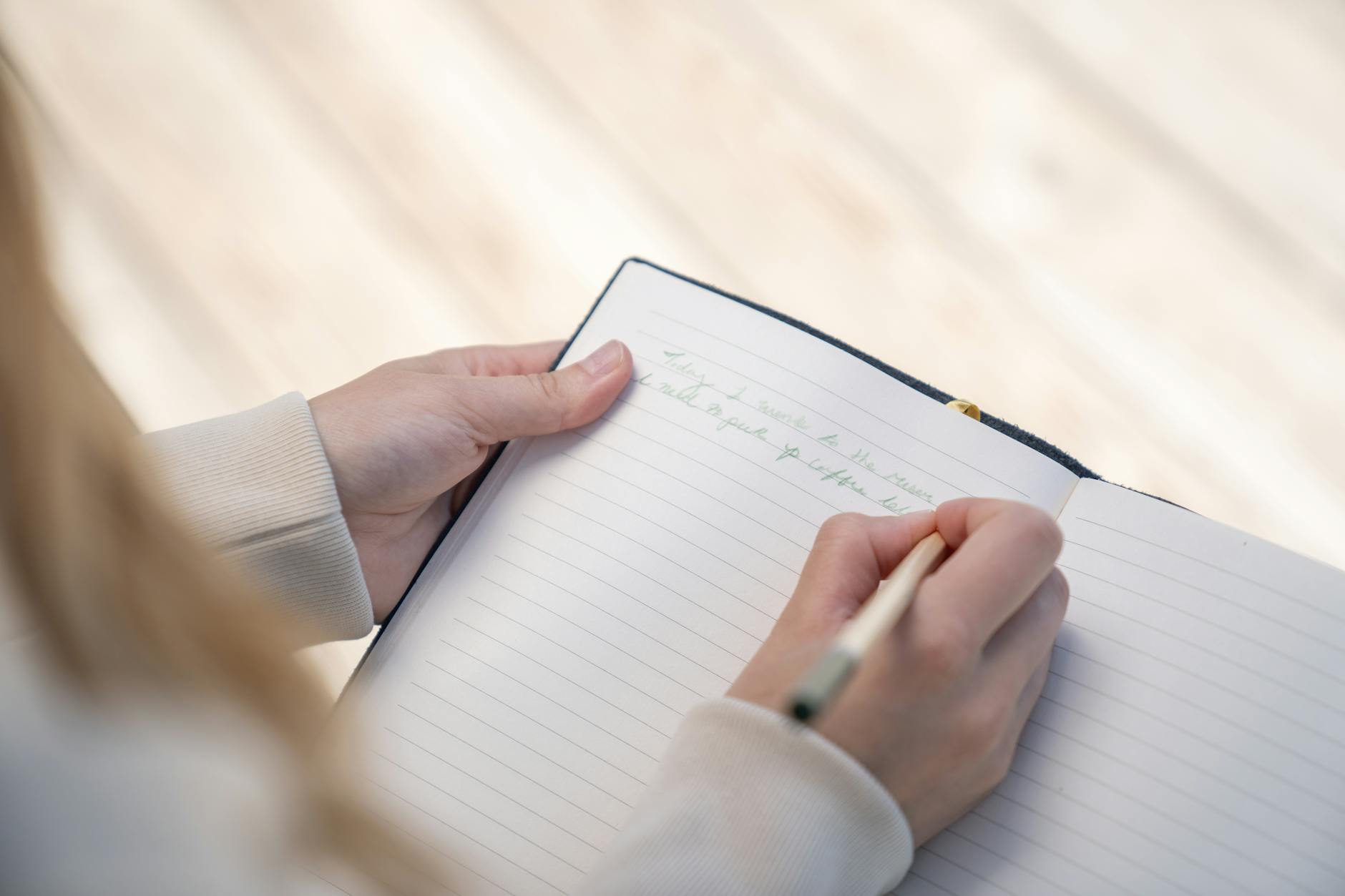 Person writing notes in a notebook with a pen