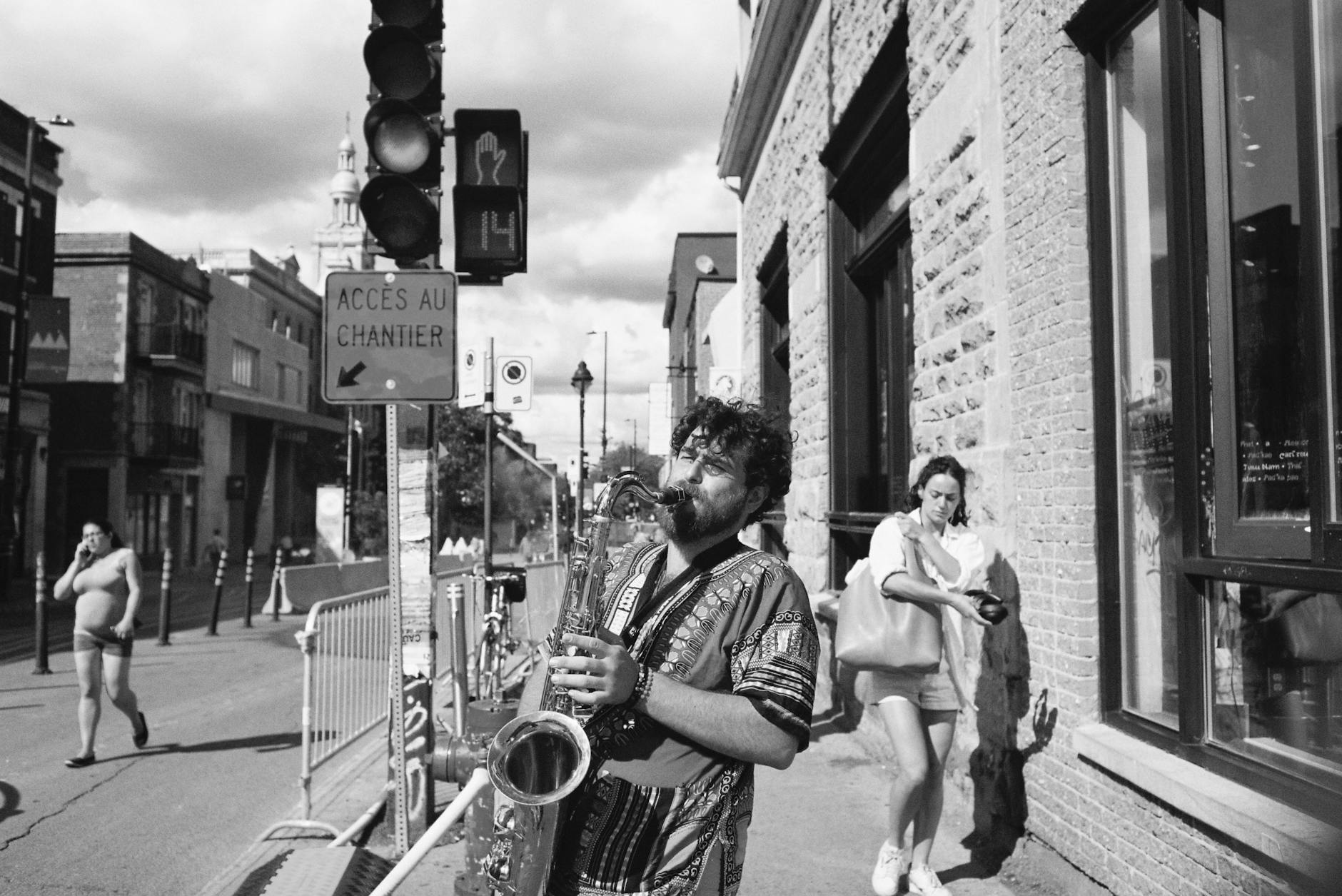 Street musician playing saxophone on a lively street at night