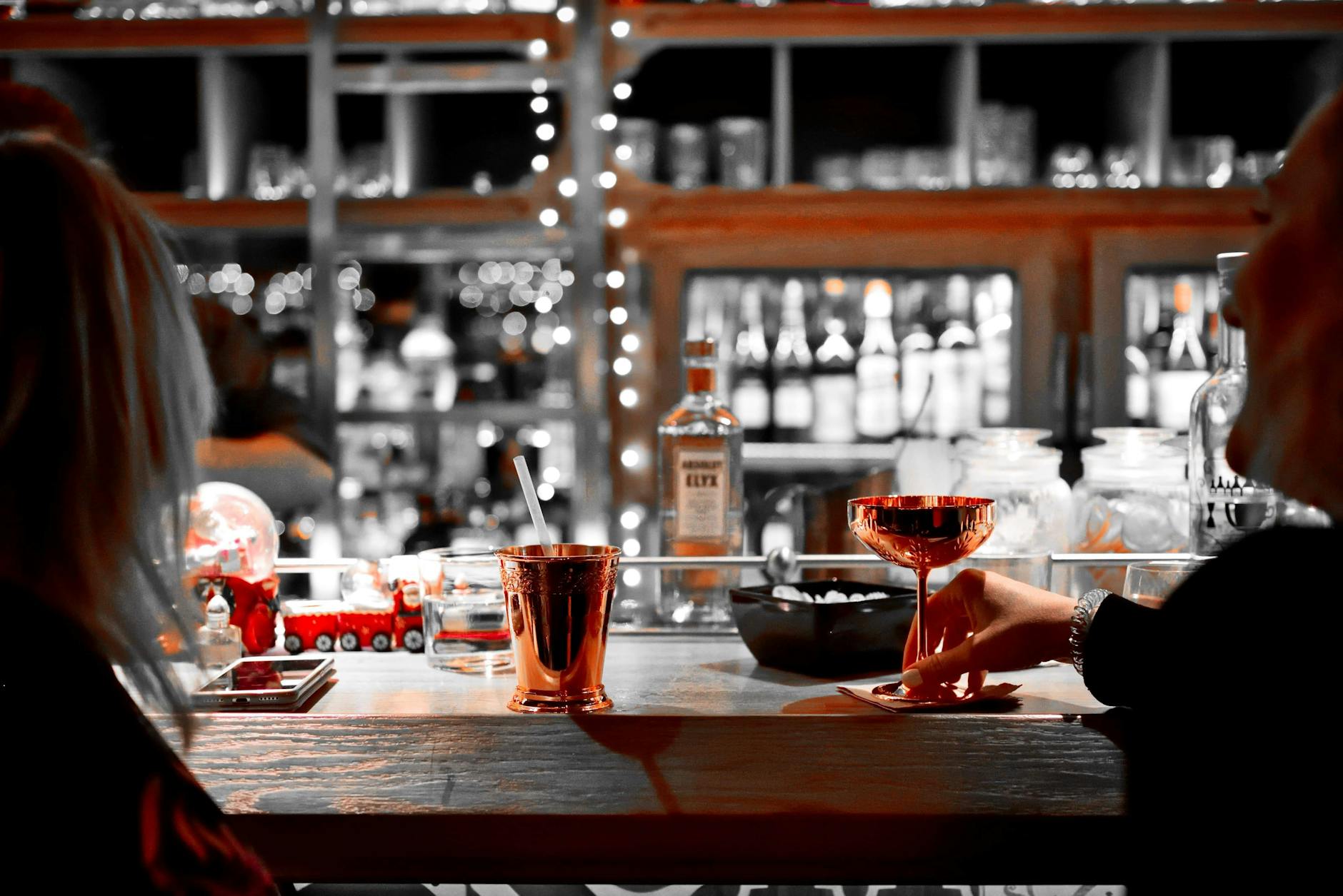 Hands holding cocktails in a festive bar scene