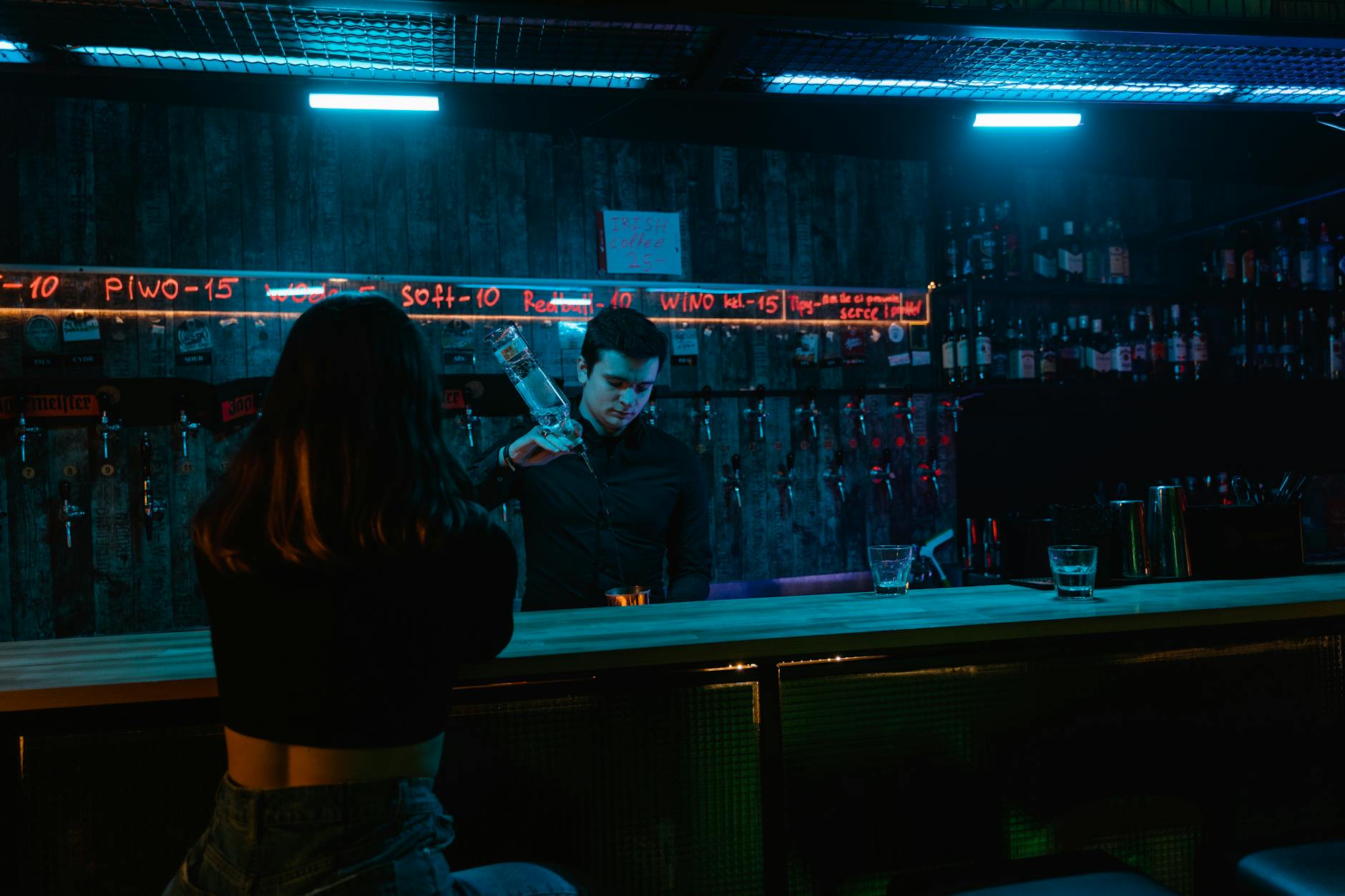 Bartender pouring a drink under neon lights