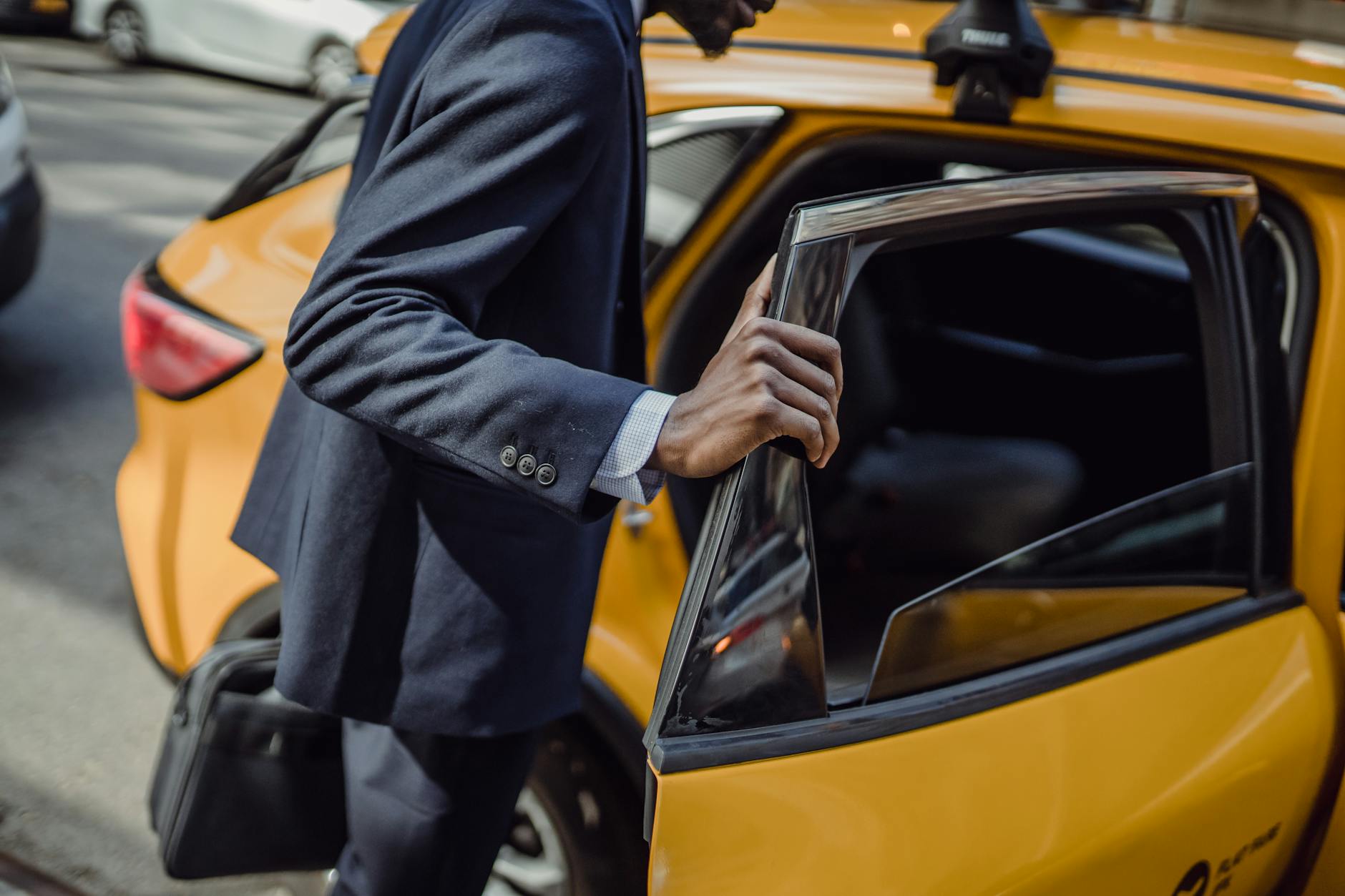 Businessman in a suit opening a taxi door on a city street