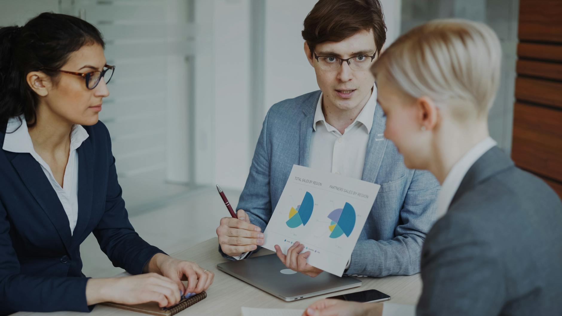 Team of professionals discussing sales strategy with charts in an office