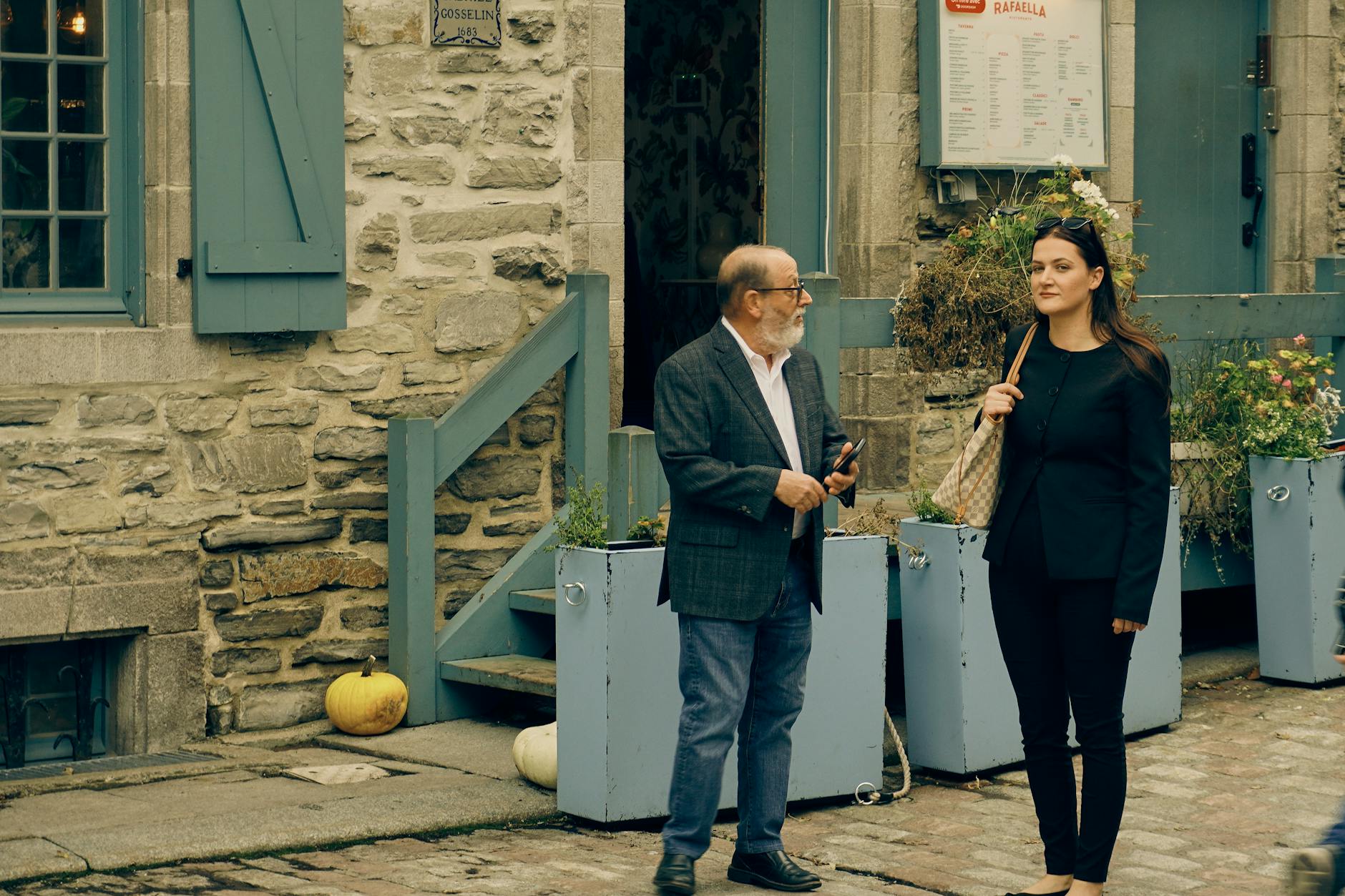 Two people talking outside a historic stone building in Quebec
