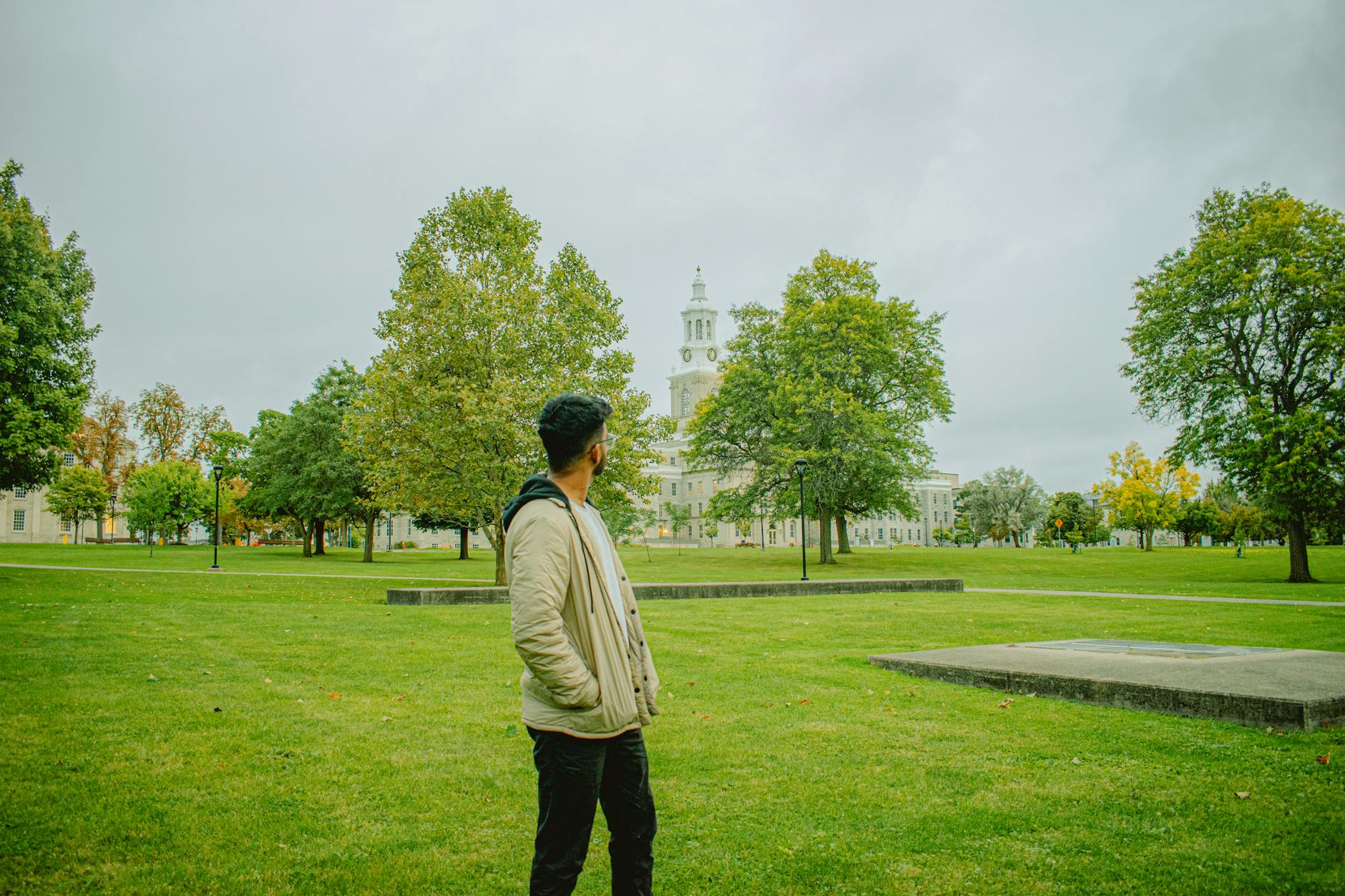 Person standing in a park near a historic building and clock tower