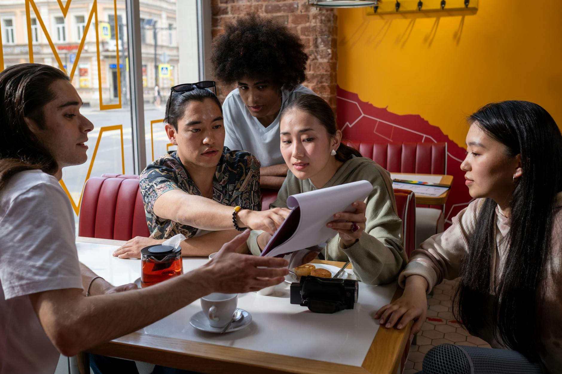 Multicultural group of young adults discussing a document in a cafe