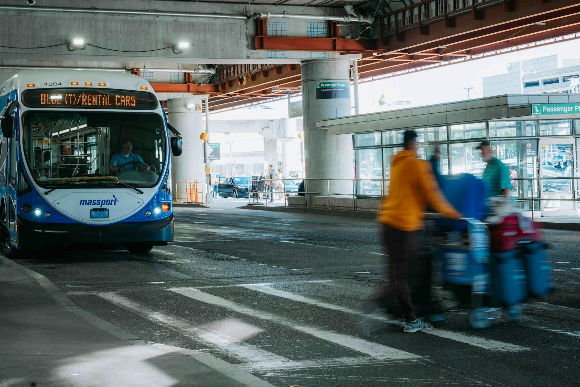 Busy airport scene with travelers and a rental car bus